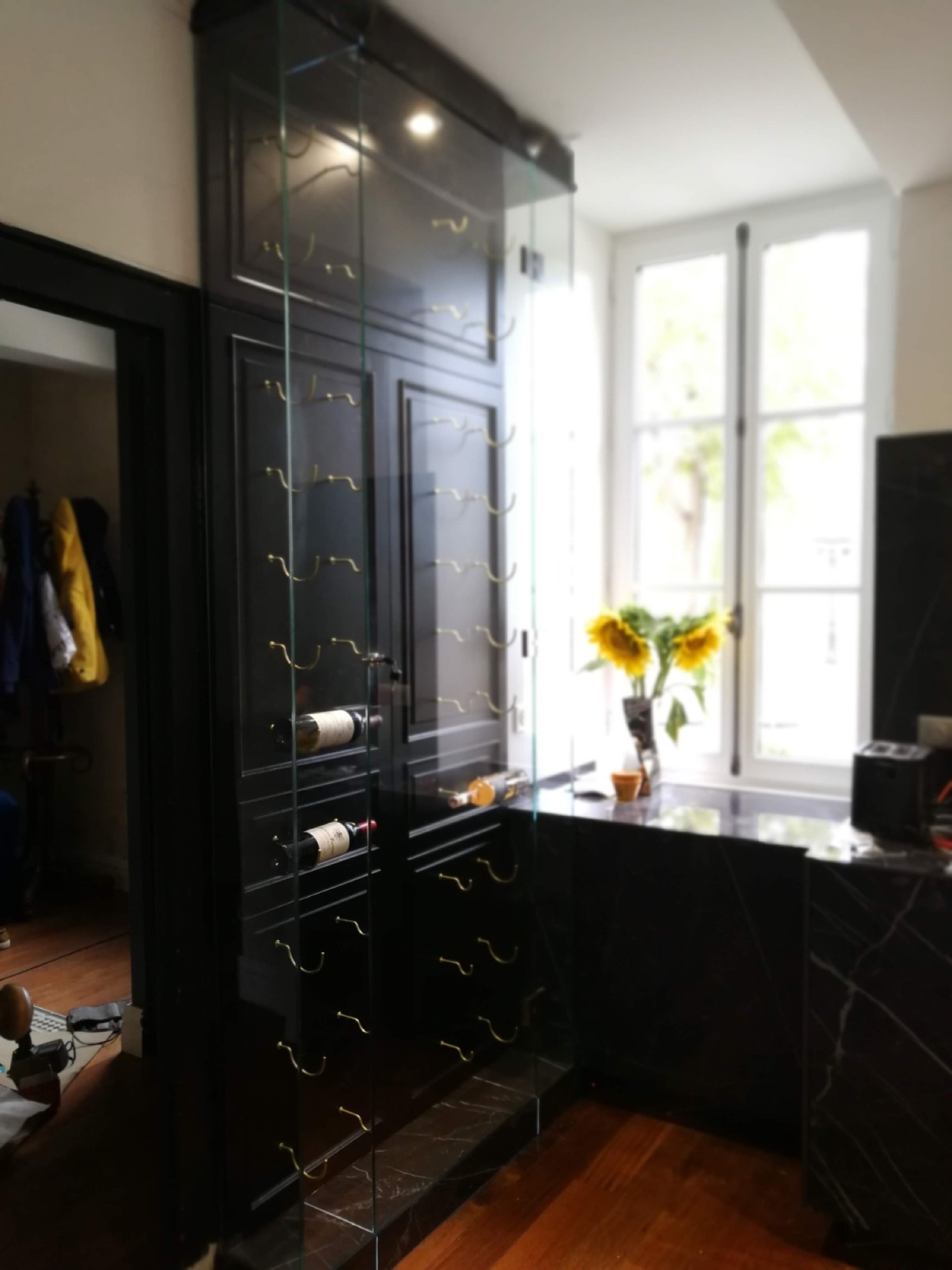 Garrafeira preta com girassóis em cozinha