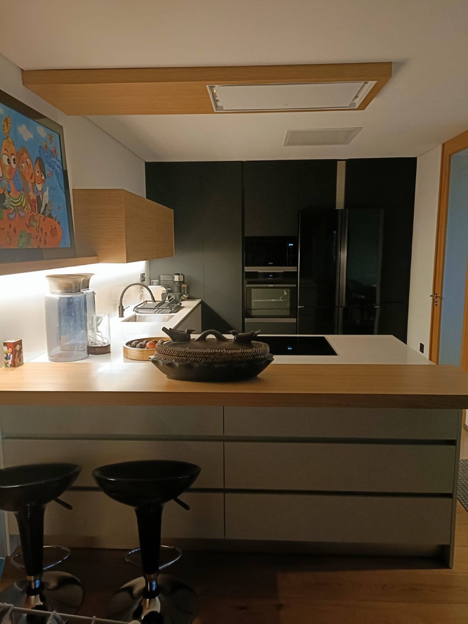 Cozinha com ilha em madeira e bancos pretos