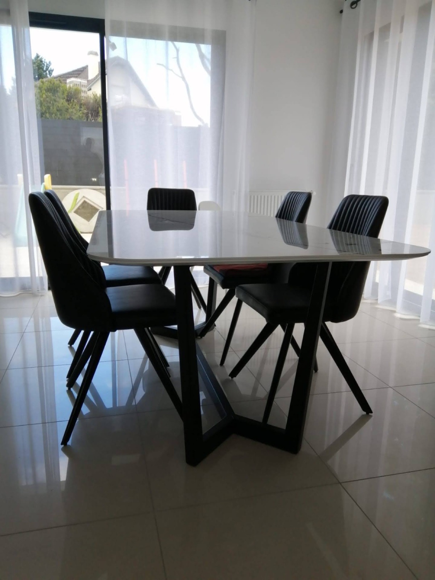 Mesa de jantar com tampo claro e cadeiras pretas