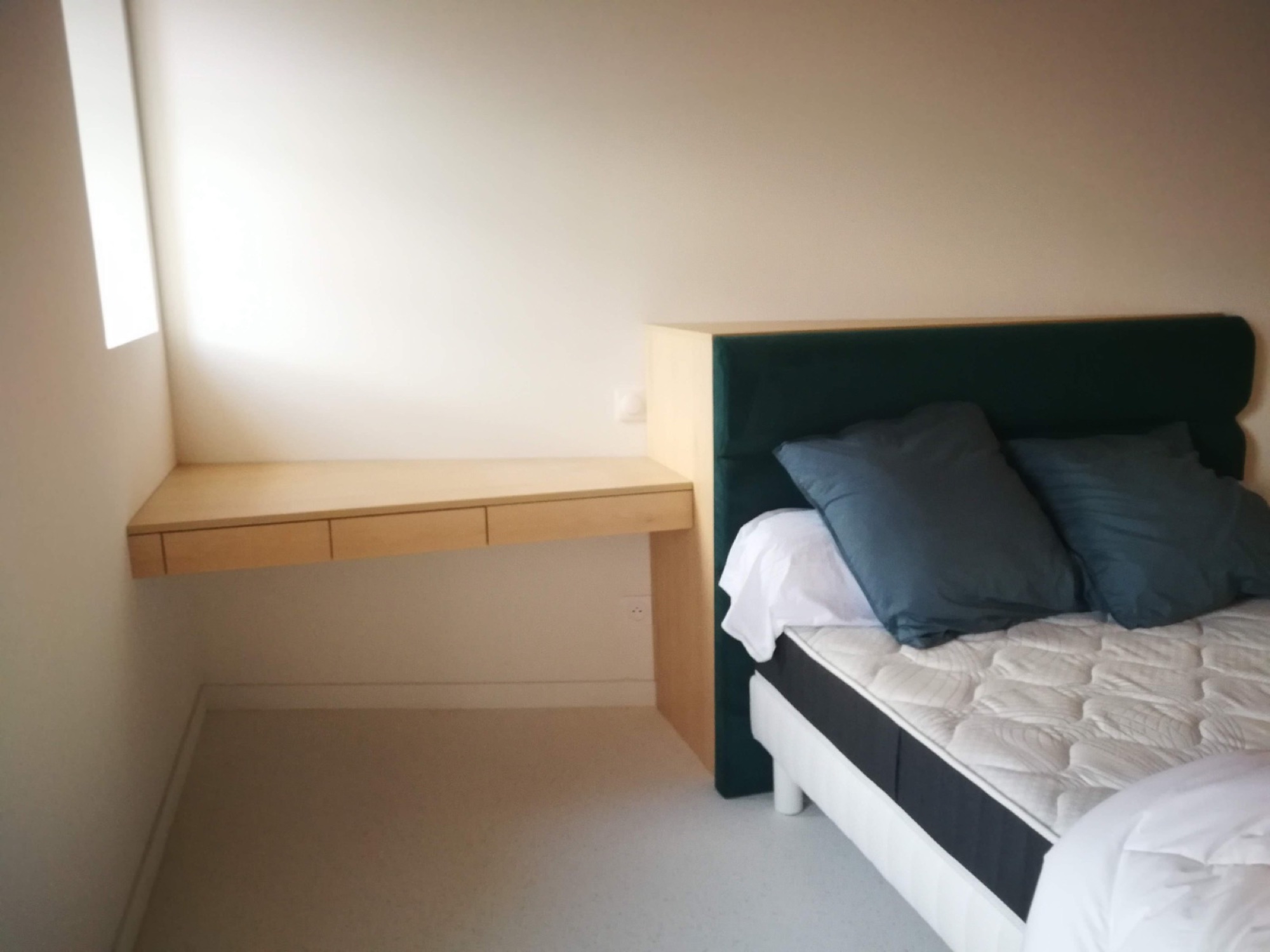 Quarto com cabeceira verde e secretária suspensa