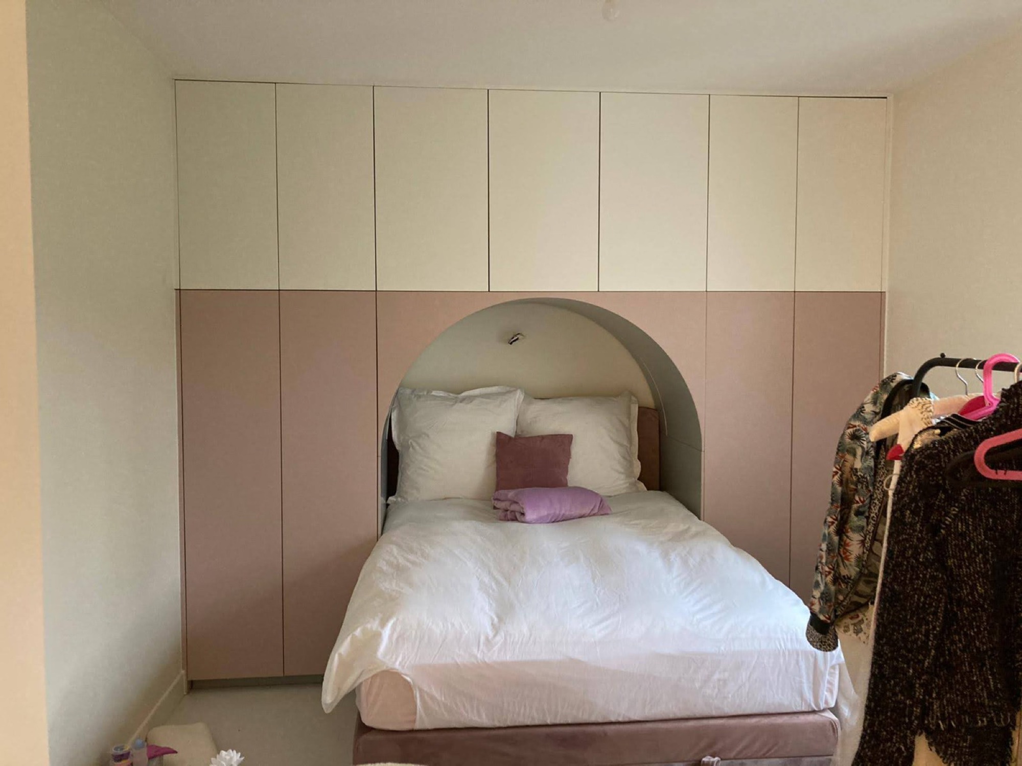 Quarto com roupeiro rosa e cabeceira arredondada