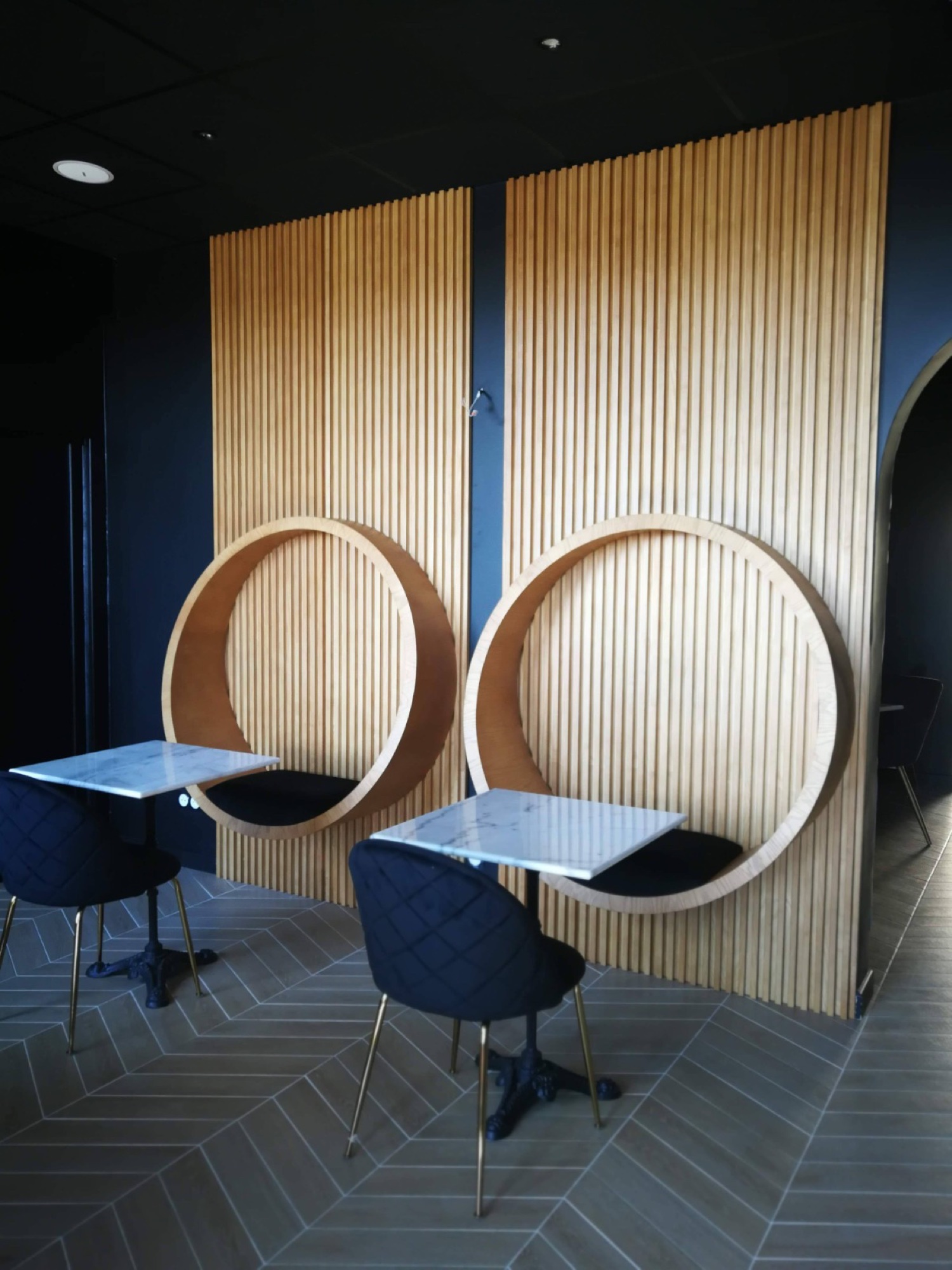 Mesas com cadeiras e parede ripada