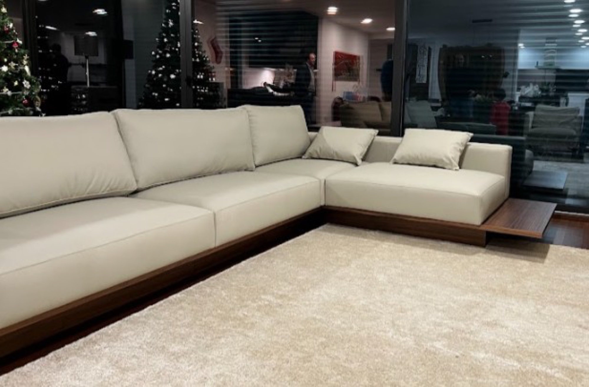 Sofá de canto branco com base em madeira e tapete