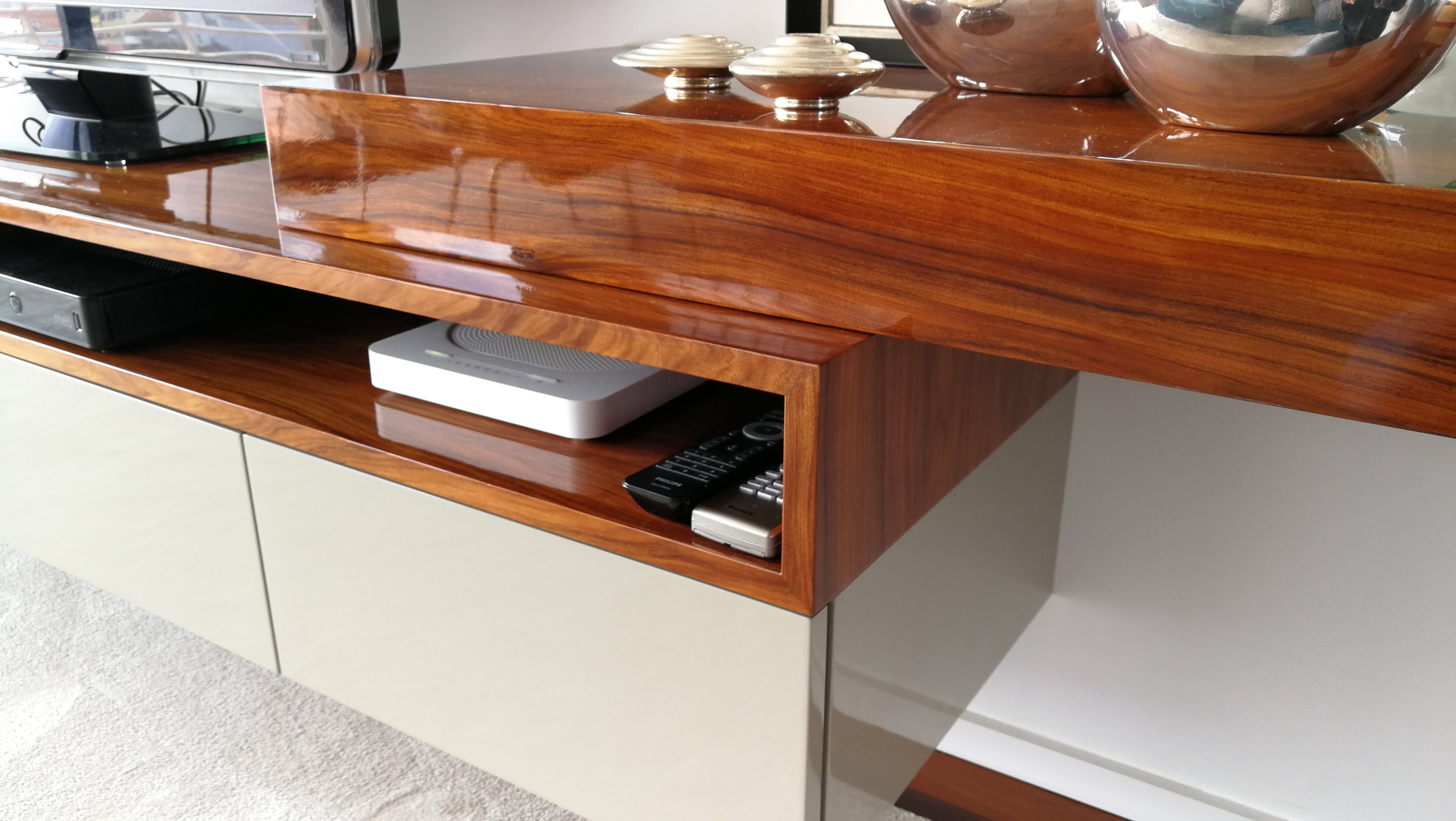 Movel de sala em madeira de nogueira alto brilho com modulos lacados em bege, nicho para equipamento audiovisual e esferas decorativas