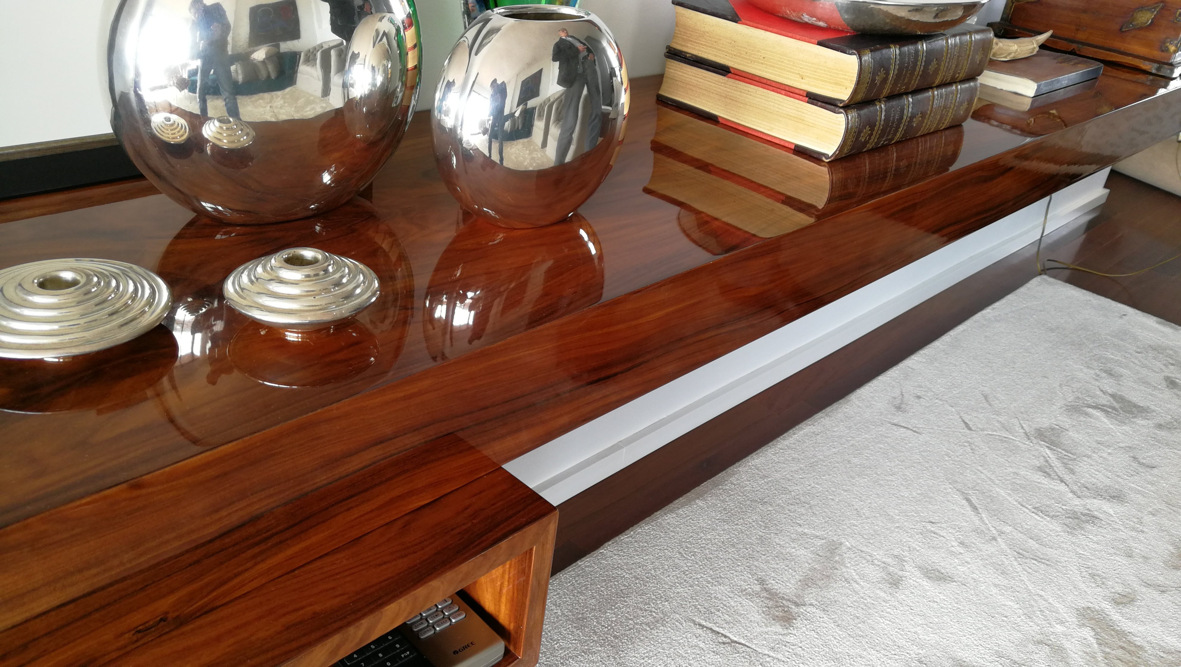 Detalhe do tampo em nogueira alto brilho do movel de TV com esferas decorativas cromadas e livros encadernados