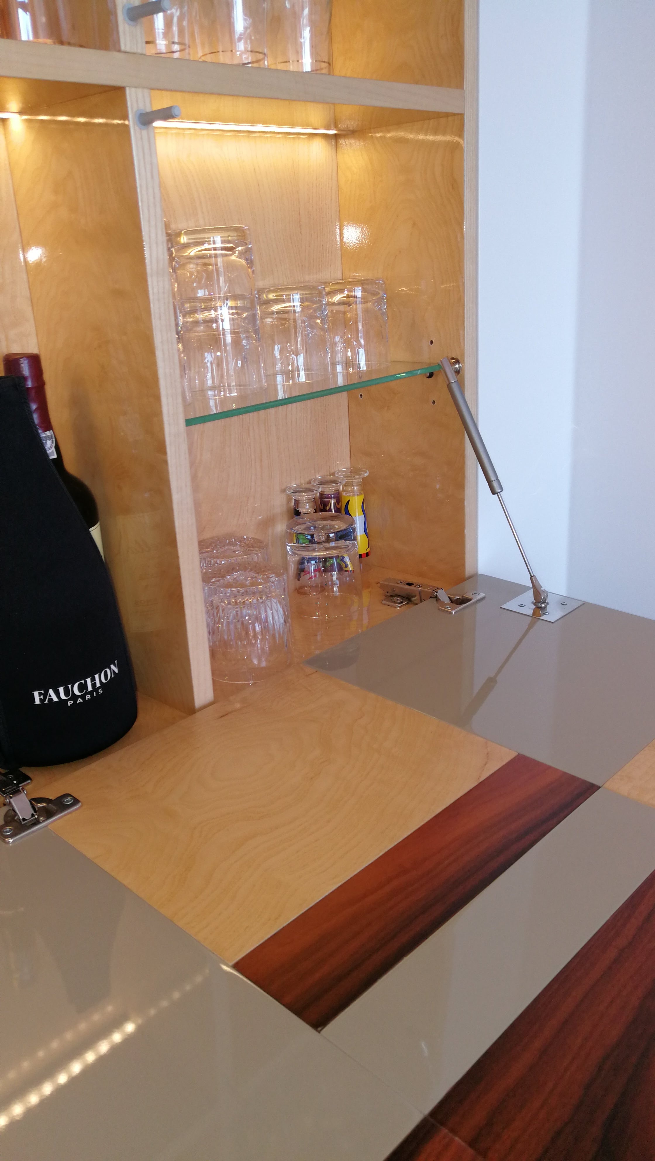 Interior do movel-bar embutido com prateleiras de vidro, iluminacao LED e copos de cristal