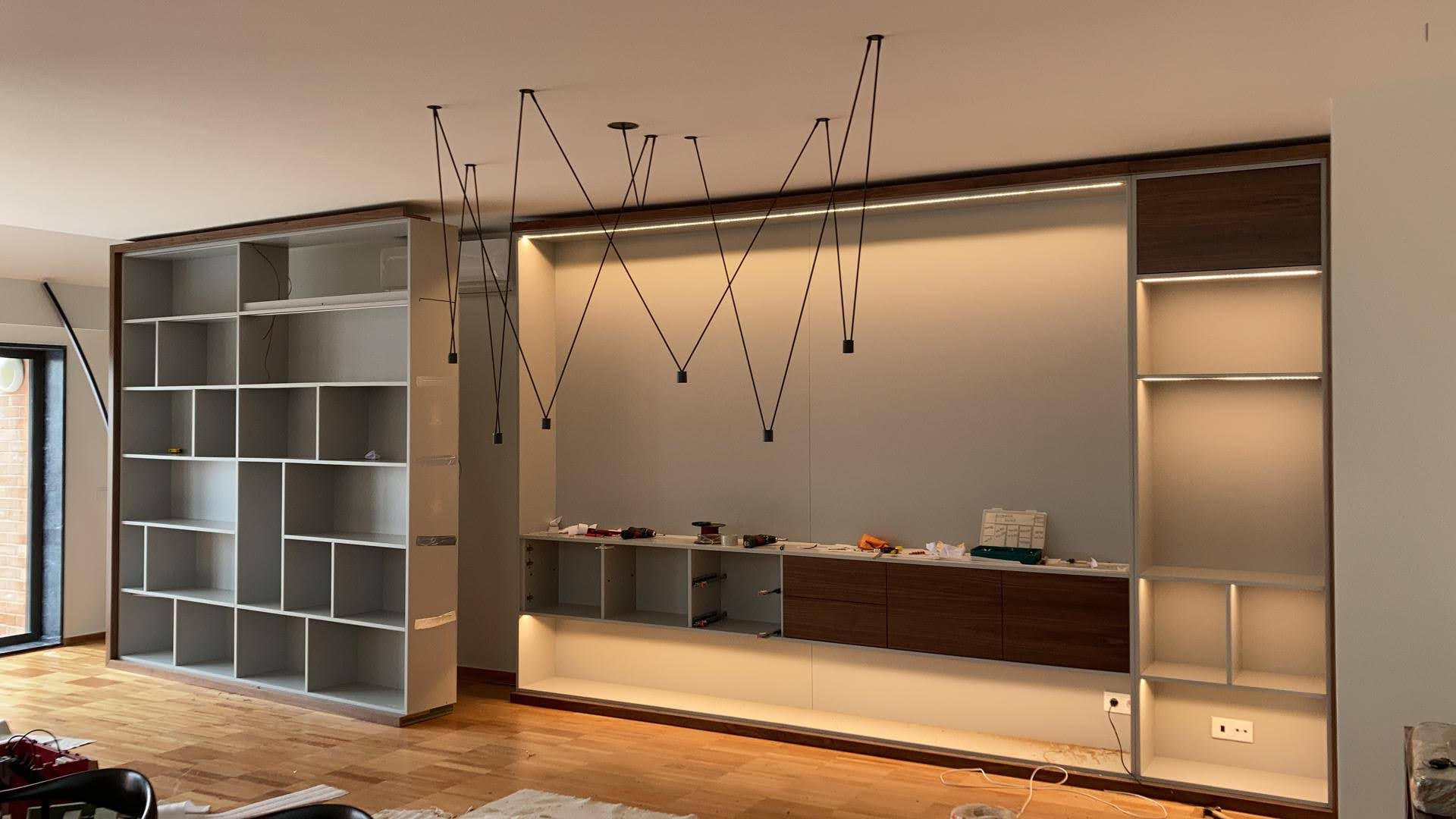 Estante embutida de parede inteira em lacado branco e nogueira com iluminacao LED e candeeiros geometricos