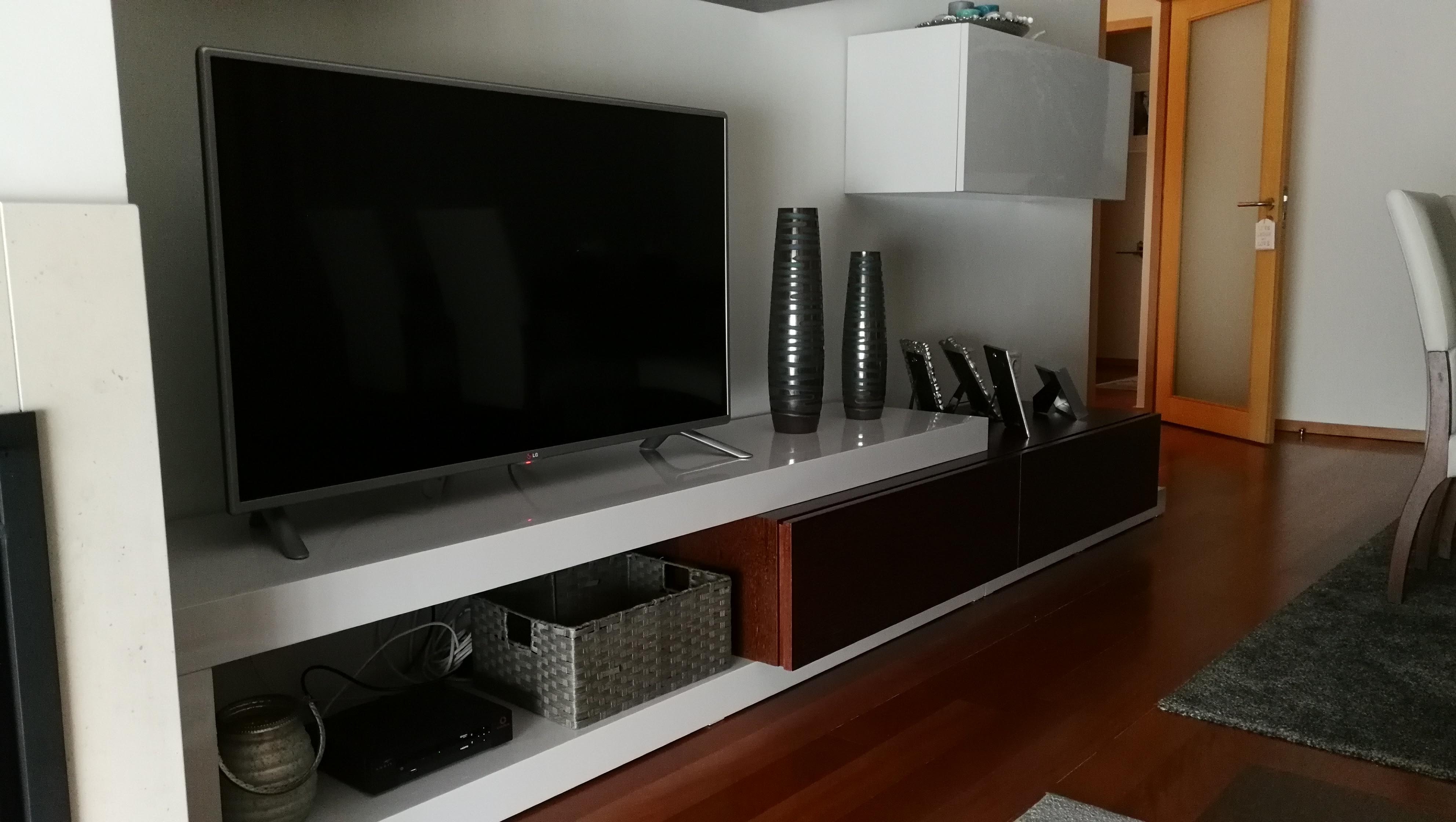 Movel de TV suspenso em lacado cinza e madeira escura alto brilho, televisao grande e jarras decorativas