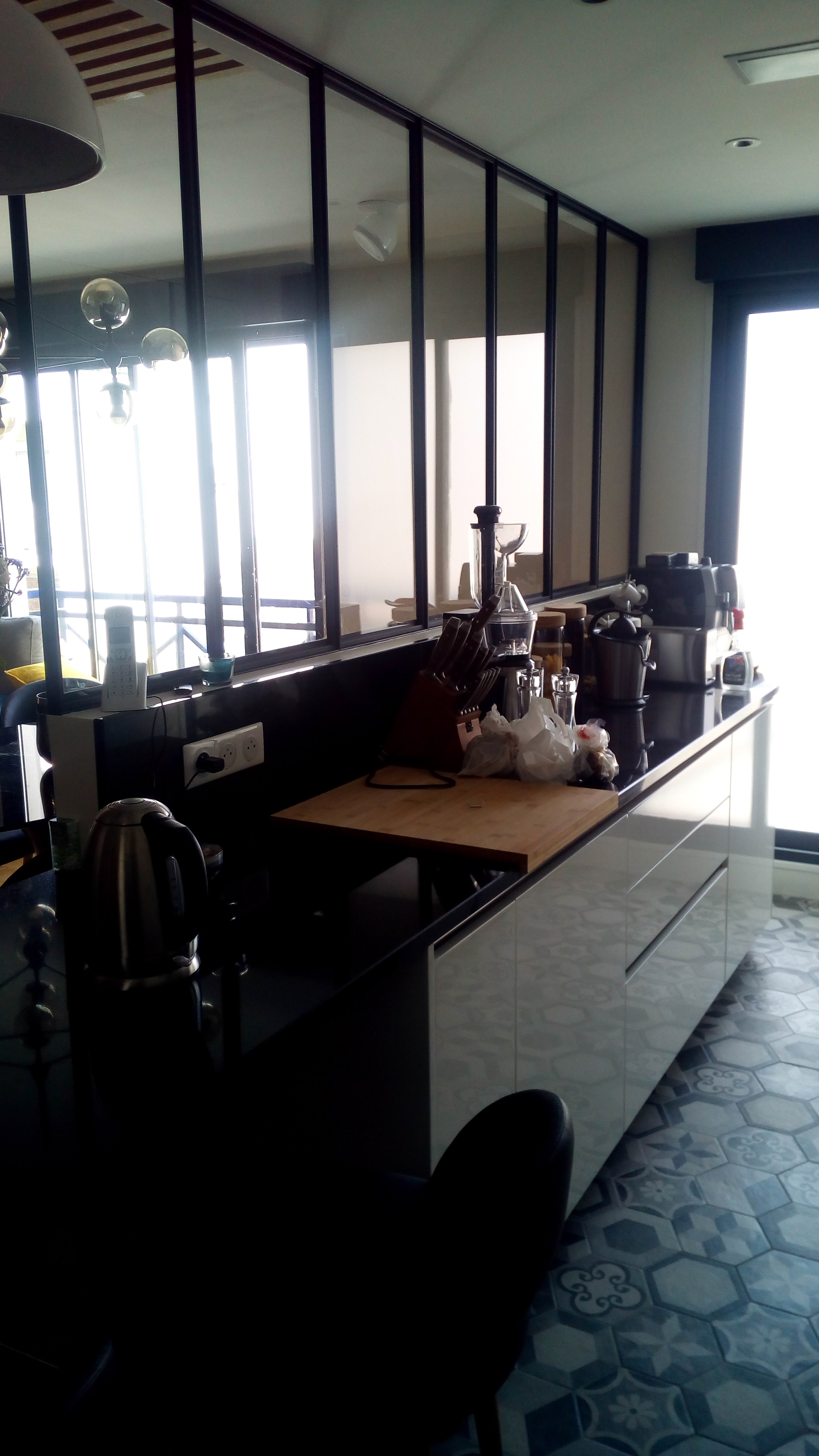 Cozinha com bancada escura e divisoria verriere em ferro preto e vidro, pavimento em mosaico hidraulico