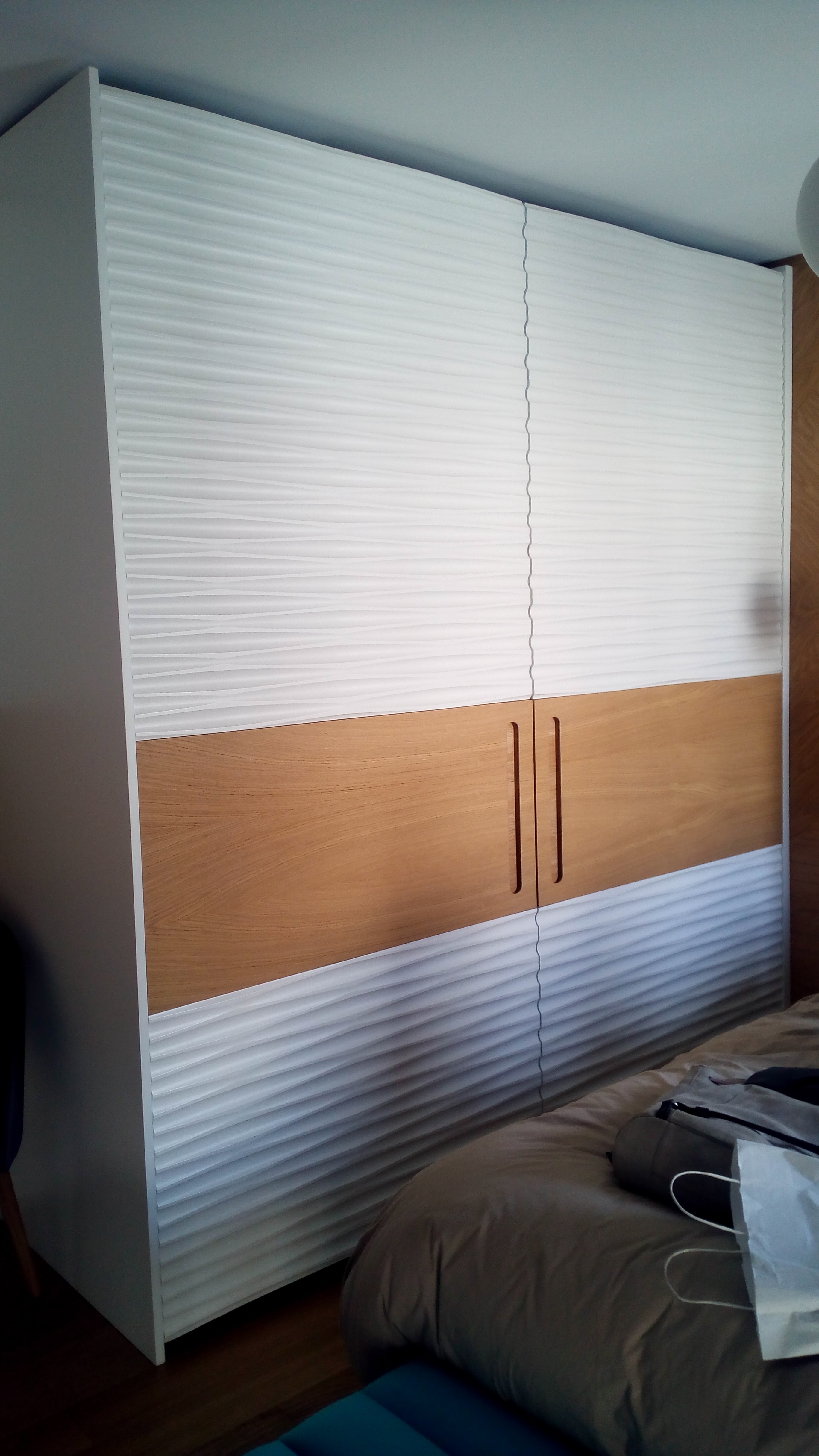 Roupeiro de portas de correr com paineis ondulados brancos e faixa central em carvalho