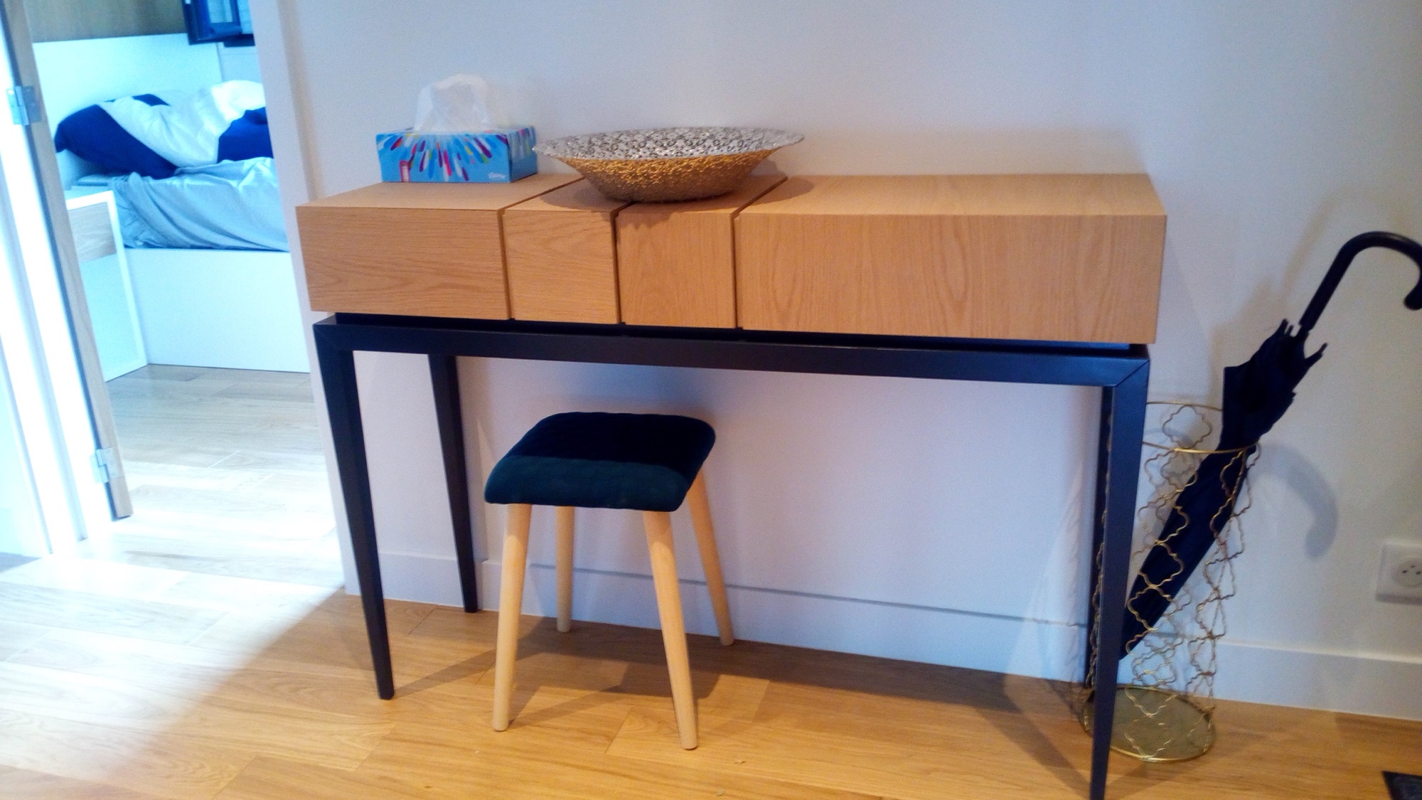 Hall com consola em carvalho e metal preto, banco estofado em veludo azul e porta-chapeus dourado