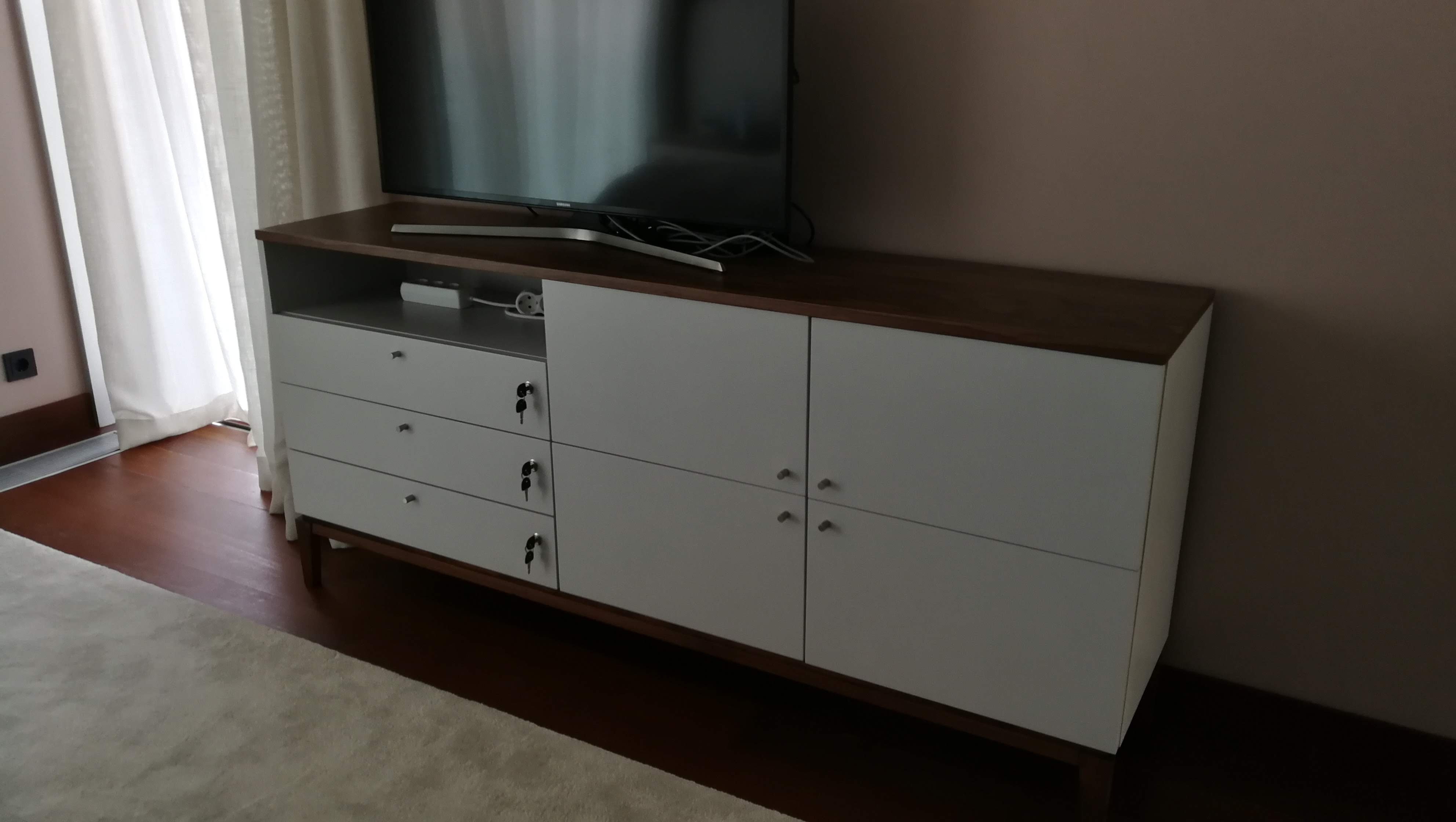 Comoda em lacado branco com tampo em nogueira e televisao, pavimento em madeira escura