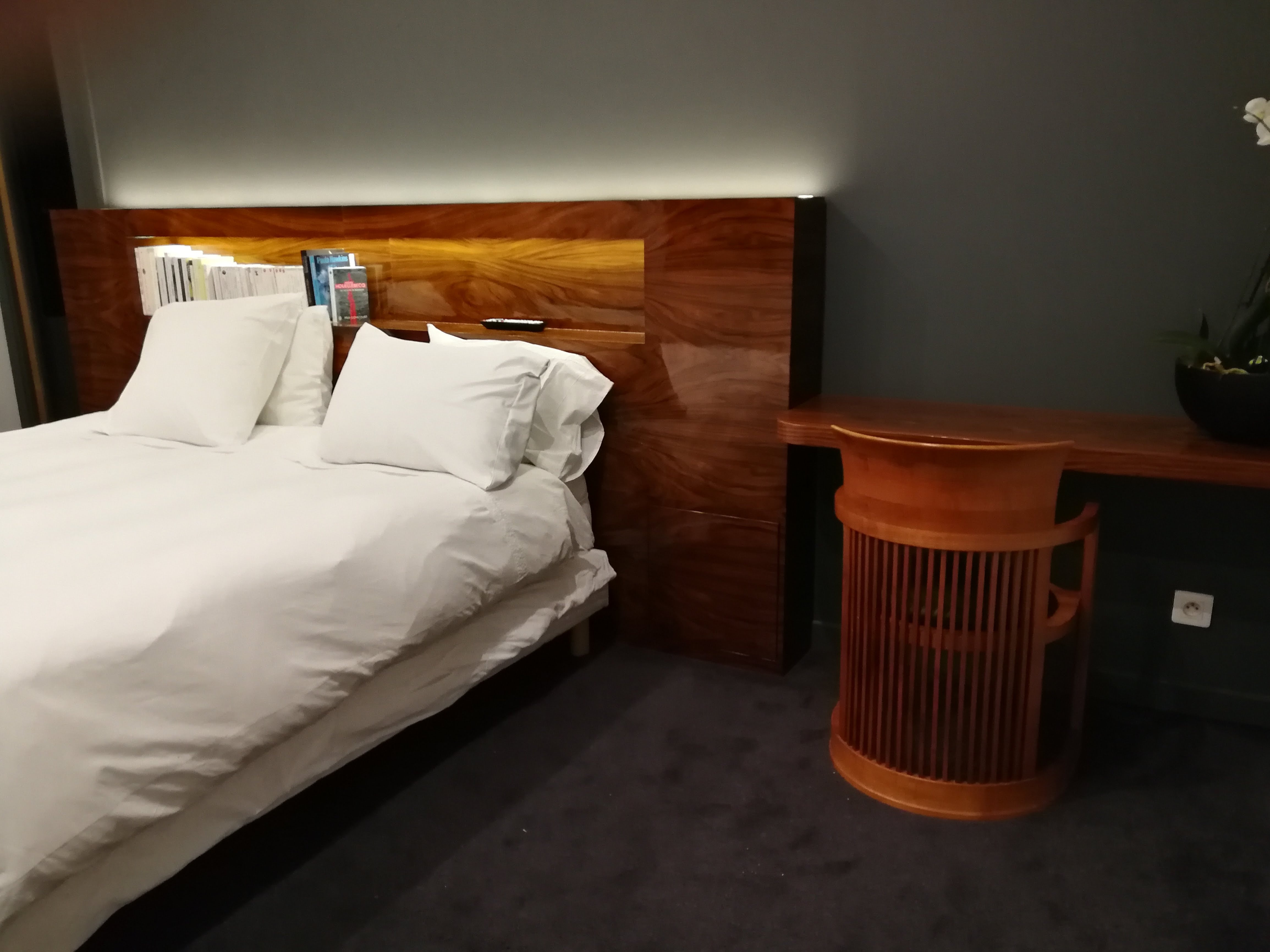 Cabeceira em nogueira com nicho, mesa de apoio decorativa em madeira torneada e orquideas brancas