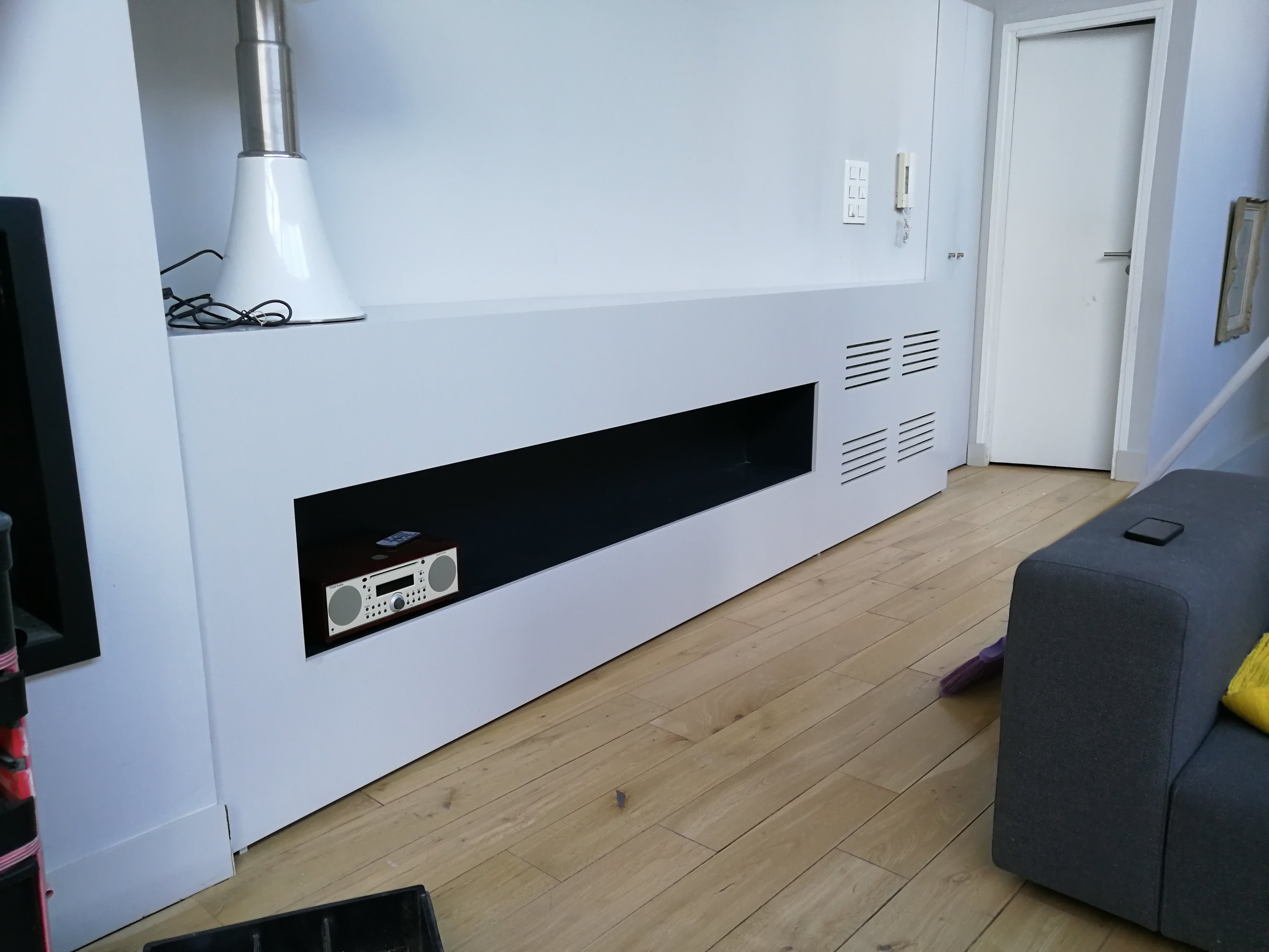 Movel de sala branco com nicho preto para aparelhagem de som e candeeiro pendente branco