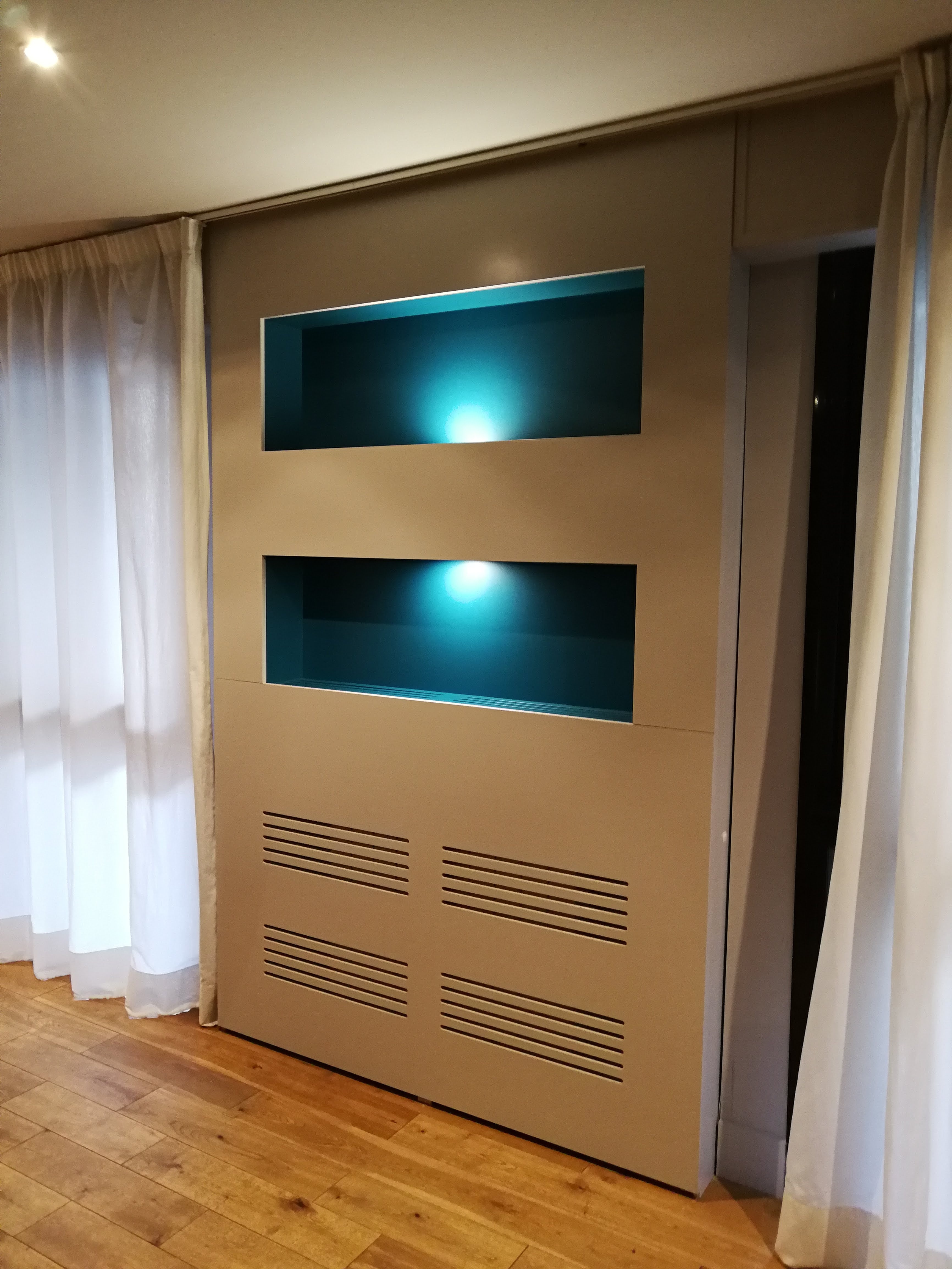 Movel com nichos iluminados em azul turquesa, lacado bege e cortinas brancas