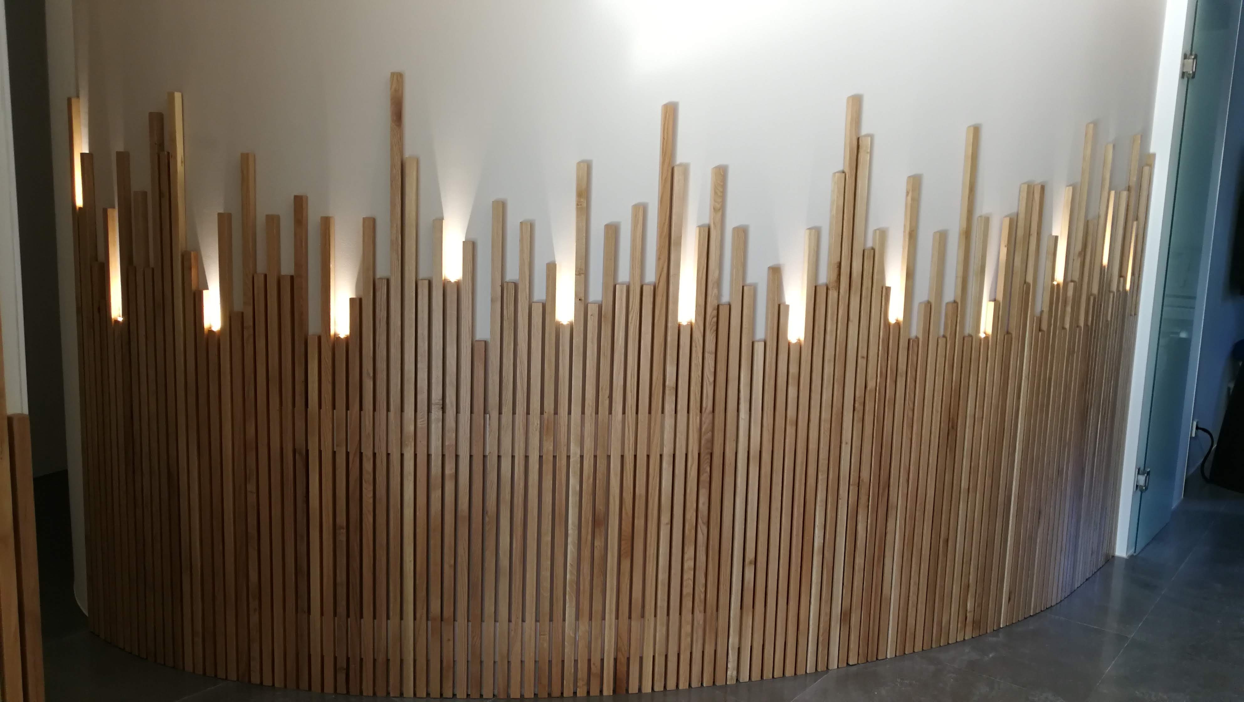 Revestimento curvo em ripas de madeira clara no hall com iluminacao LED entre ripas