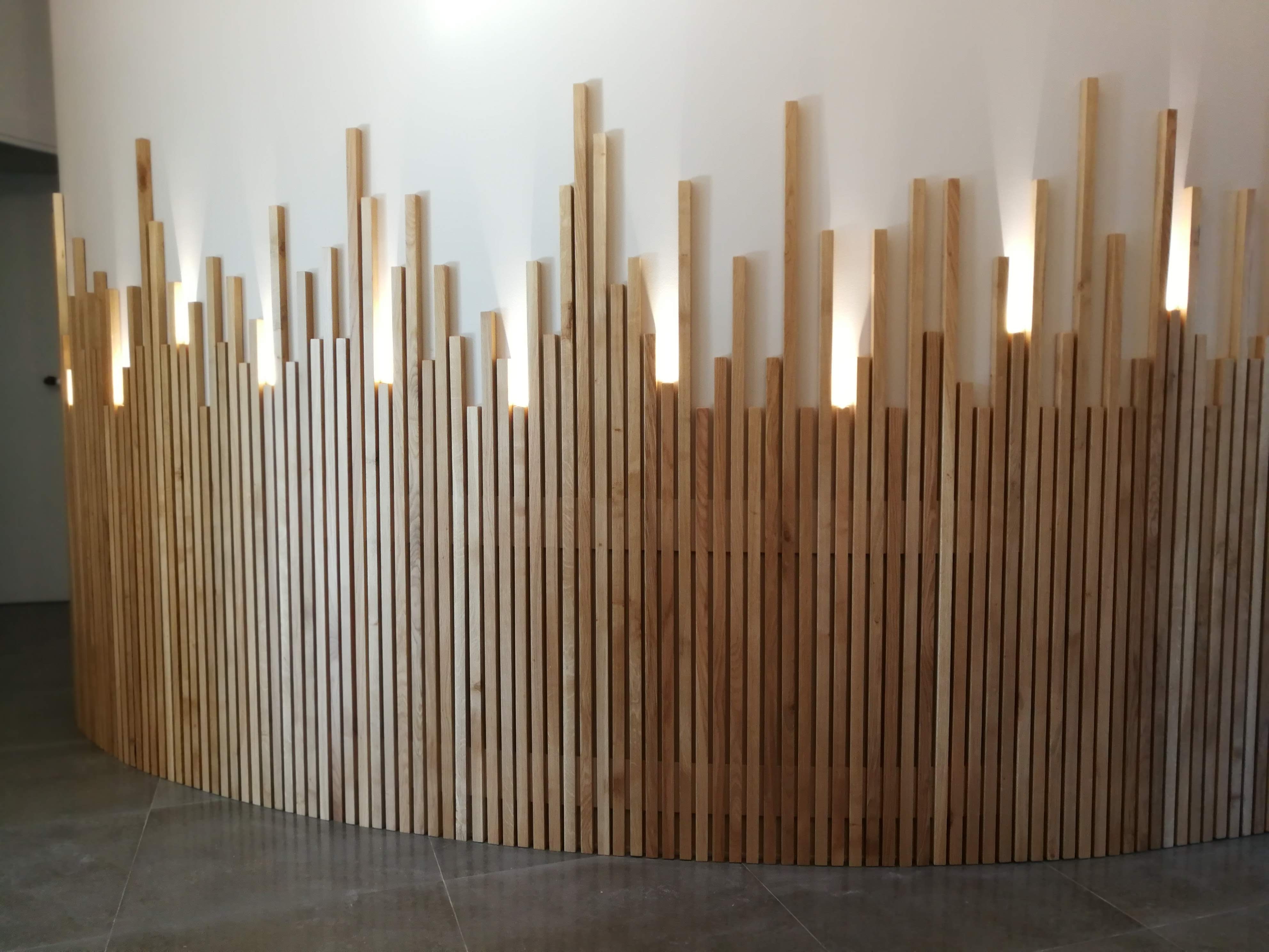 Revestimento curvo em ripas verticais de madeira clara com iluminacao LED no hall