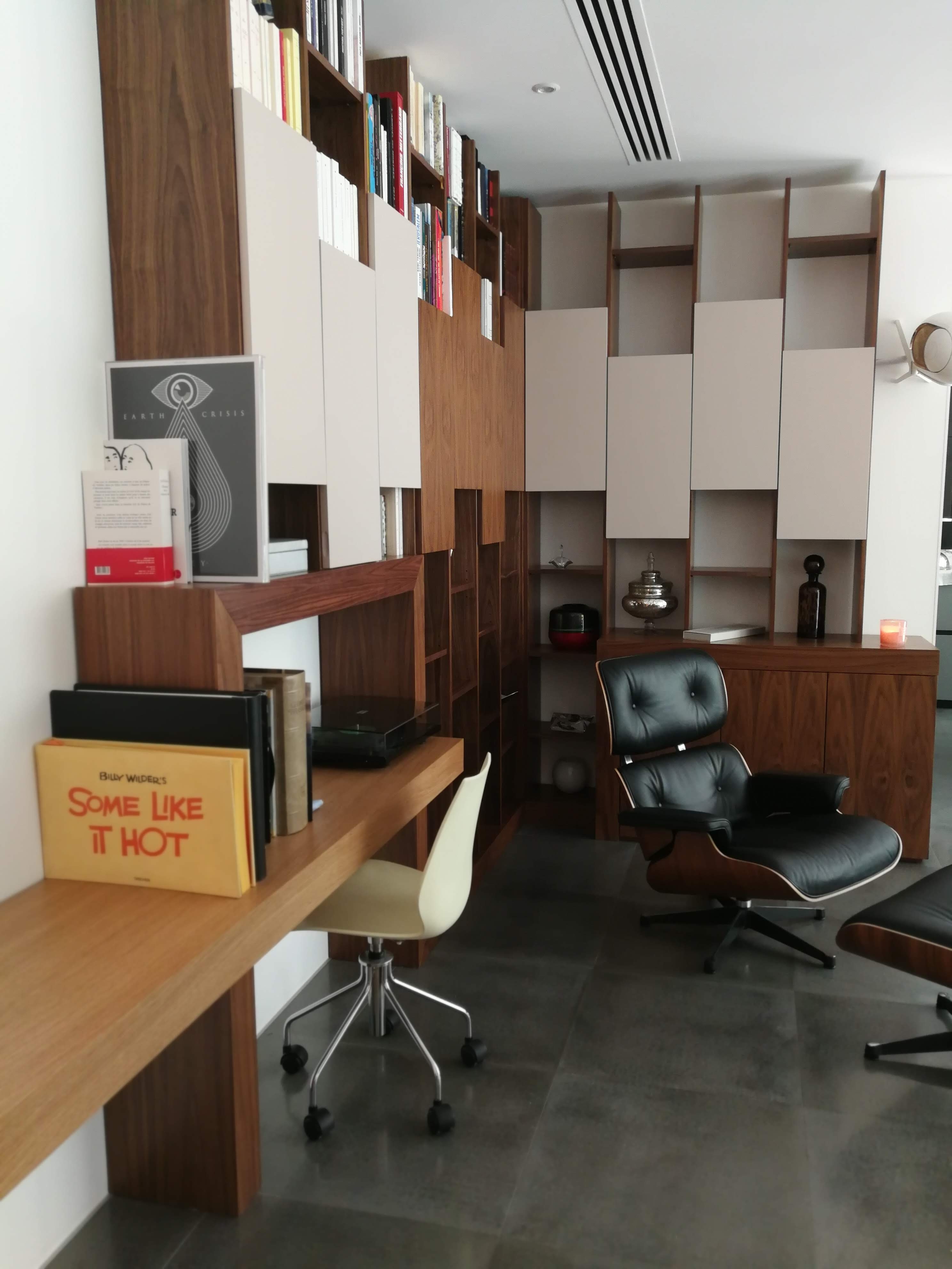 Corredor com revestimento curvo em ripas de madeira clara iluminadas e pavimento em pedra cinza