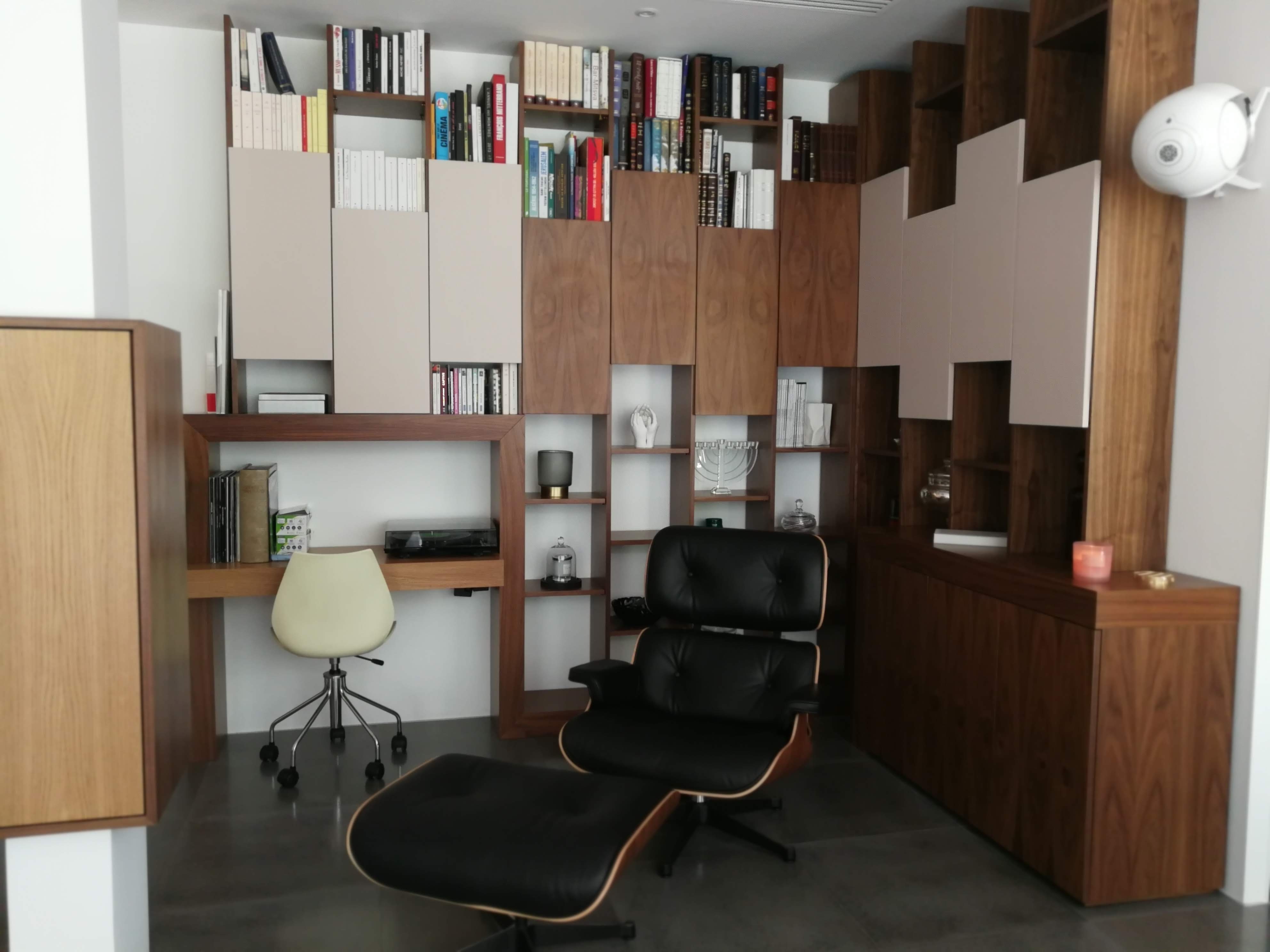 Escritorio com secretaria em nogueira, cadeira giratoria branca, poltrona Eames e estante modular
