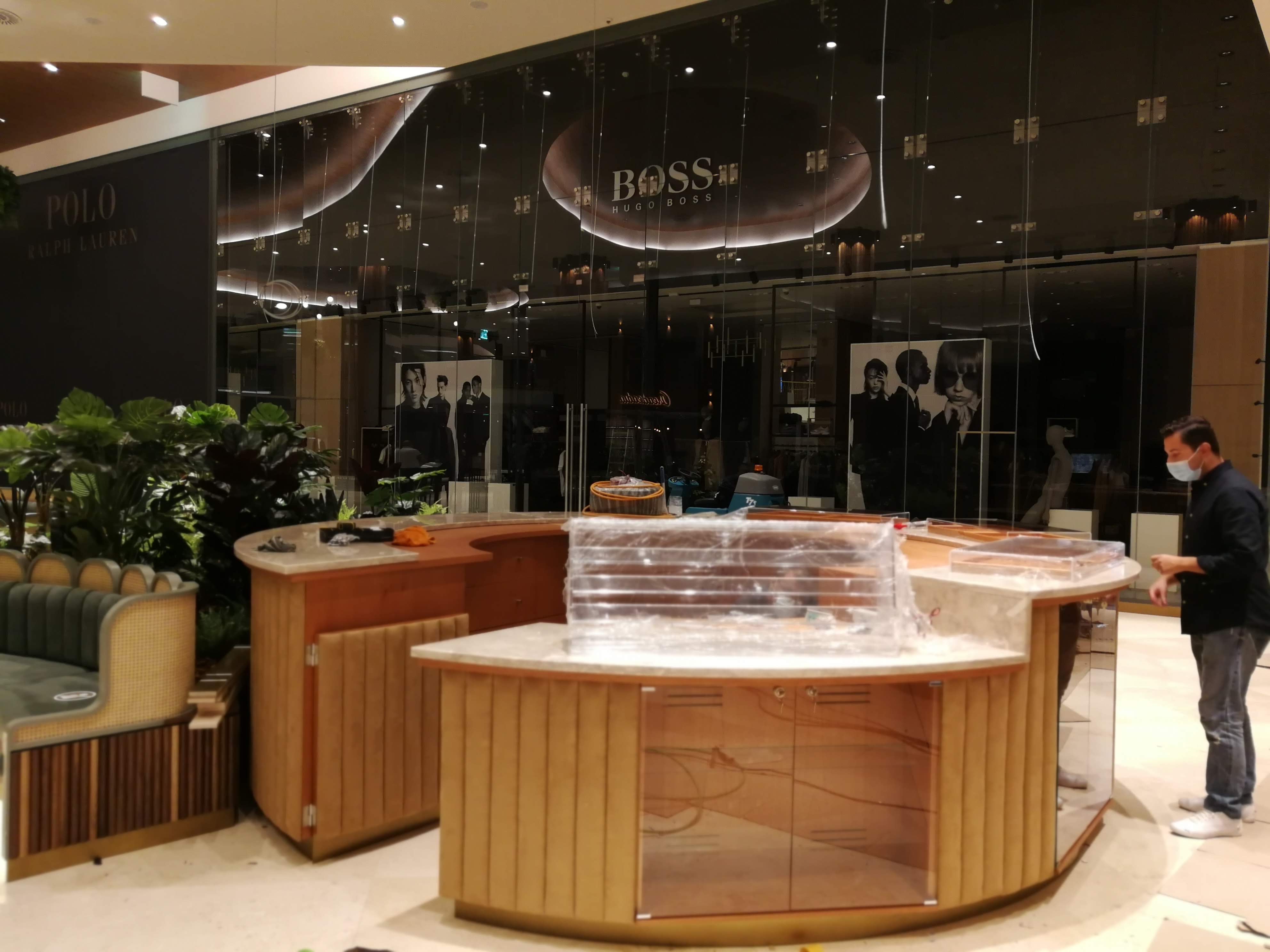 Perspetiva geral do quiosque com vitrinas em vidro curvado, tampo em marmore e zona ajardinada lateral