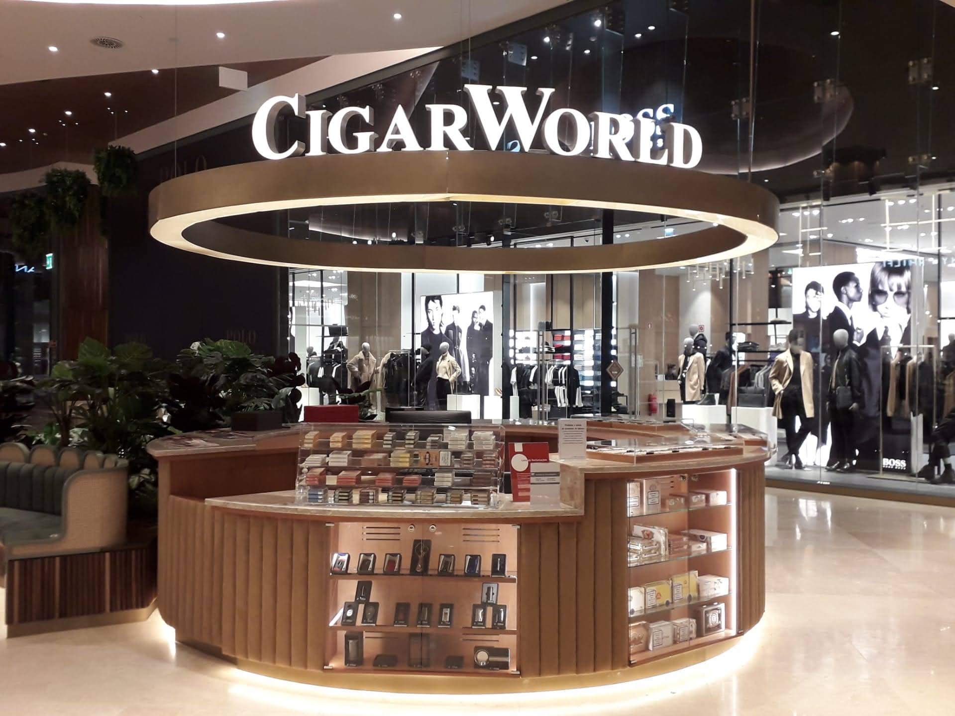 Quiosque CigarWorld finalizado com letreiro circular dourado iluminado, vitrinas com produtos expostos e iluminacao LED