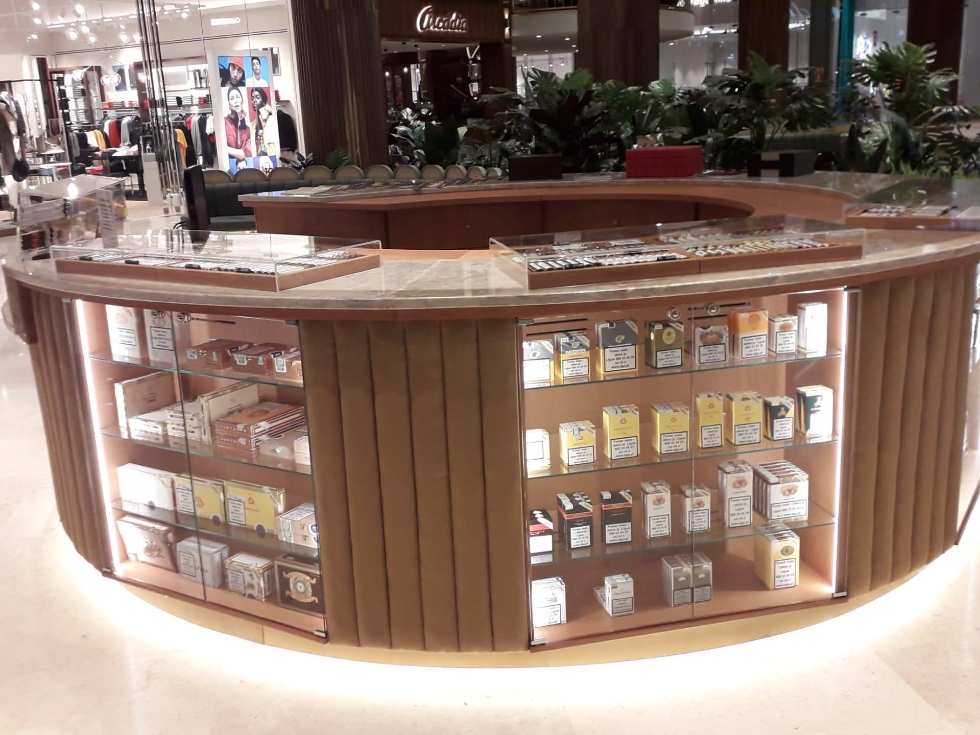 Vista traseira do balcao curvo com prateleiras em vidro iluminadas, expositores e base com iluminacao LED inferior