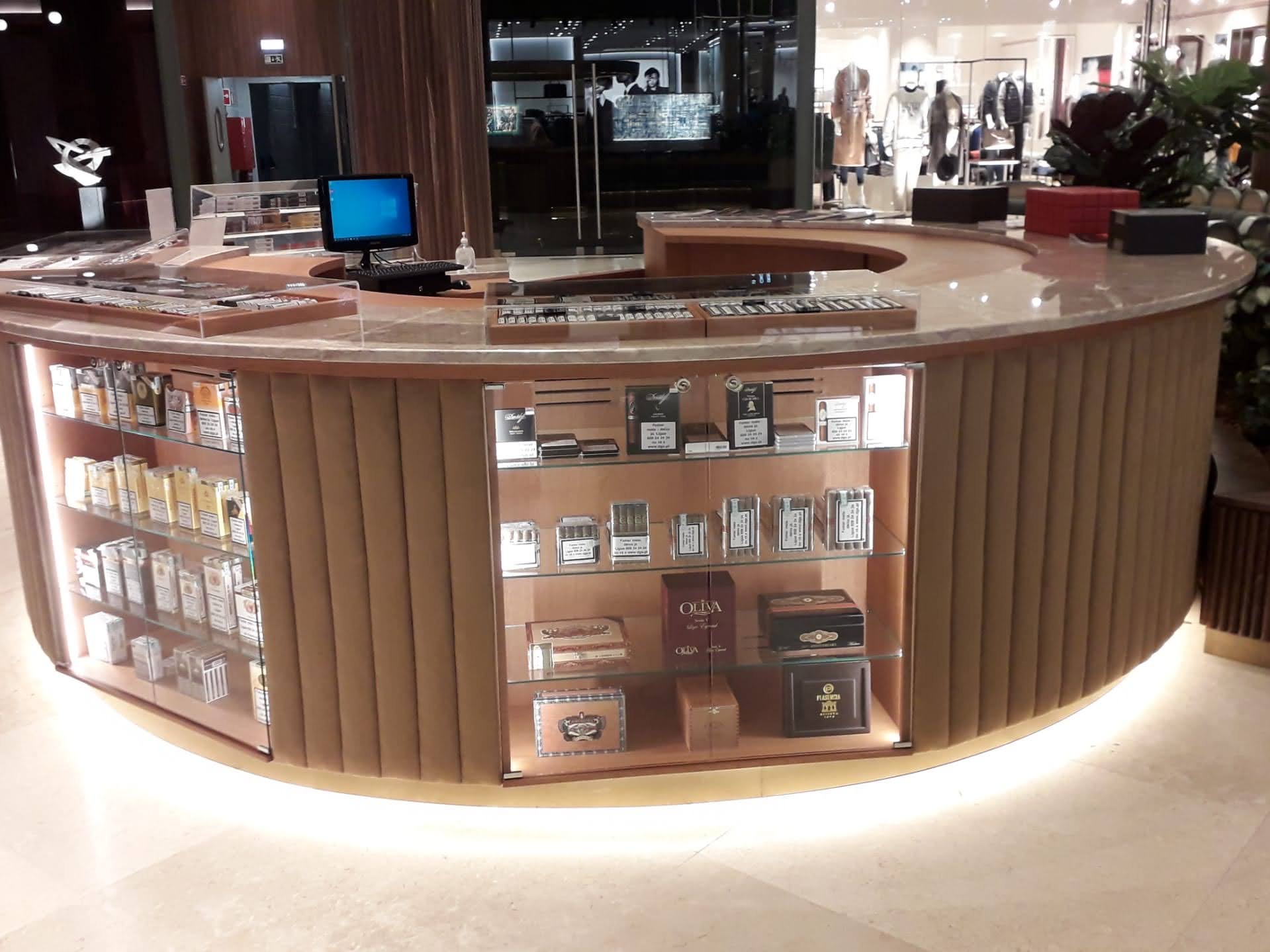 Detalhe do balcao com vitrinas iluminadas, zona de caixa registadora e expositores de charutos em vidro