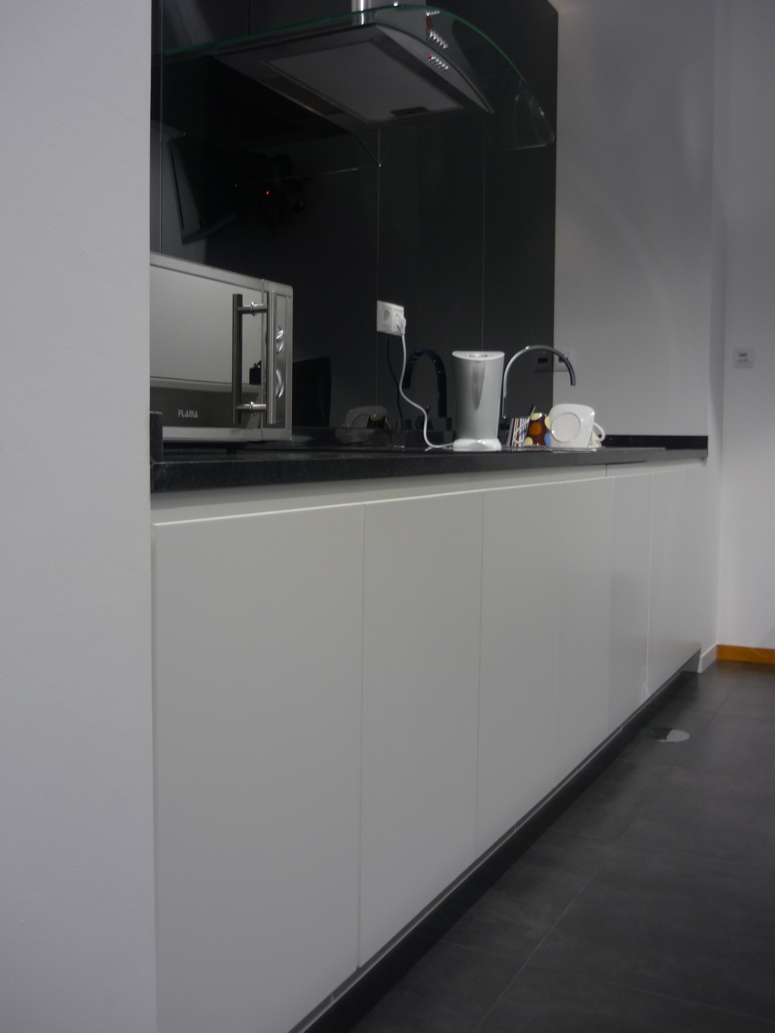 Kitchenette corporativa com armarios brancos e bancada em granito negro