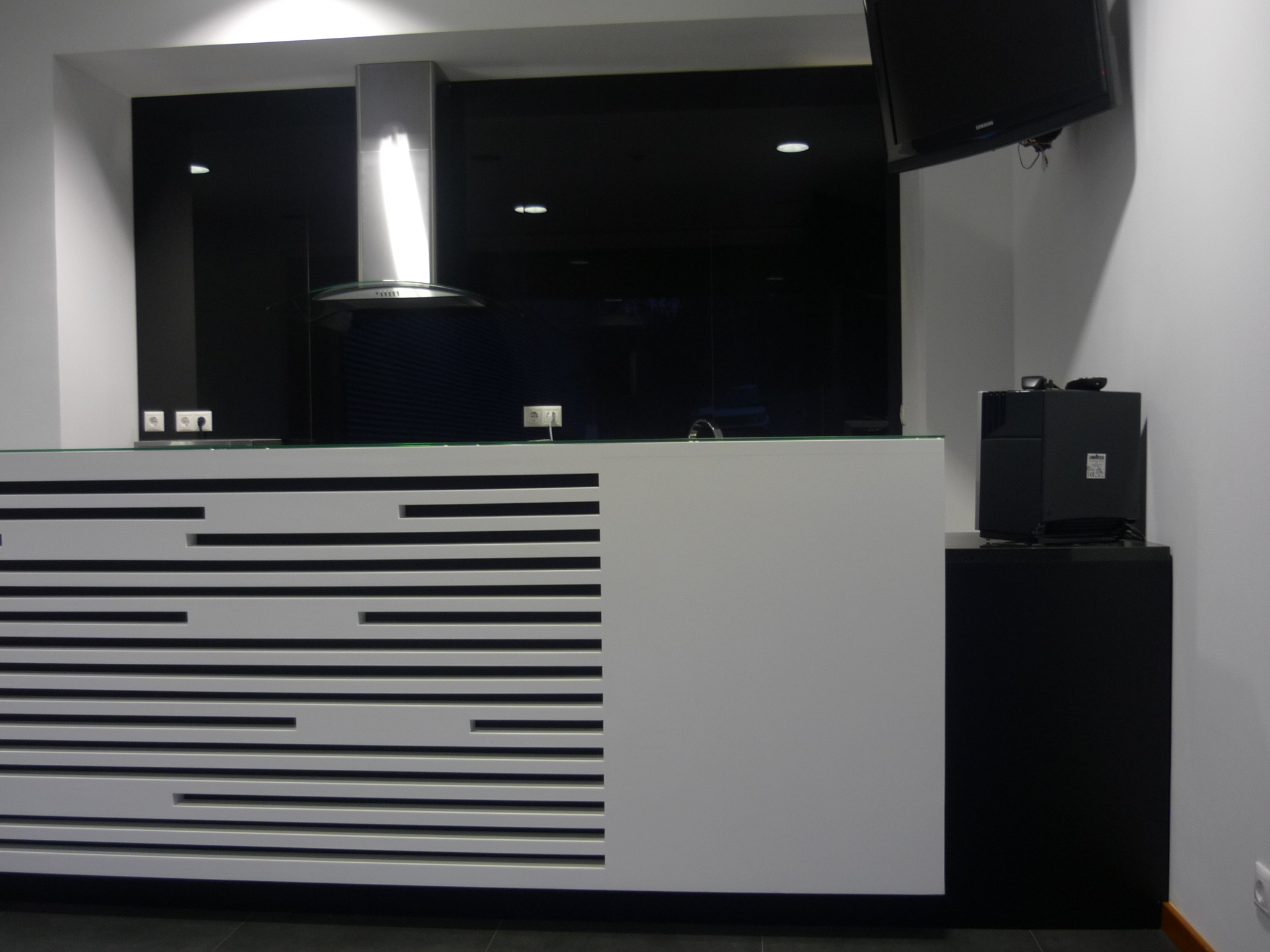 Vista geral do balcao com ilha central, zona de cafe e TV suspensa