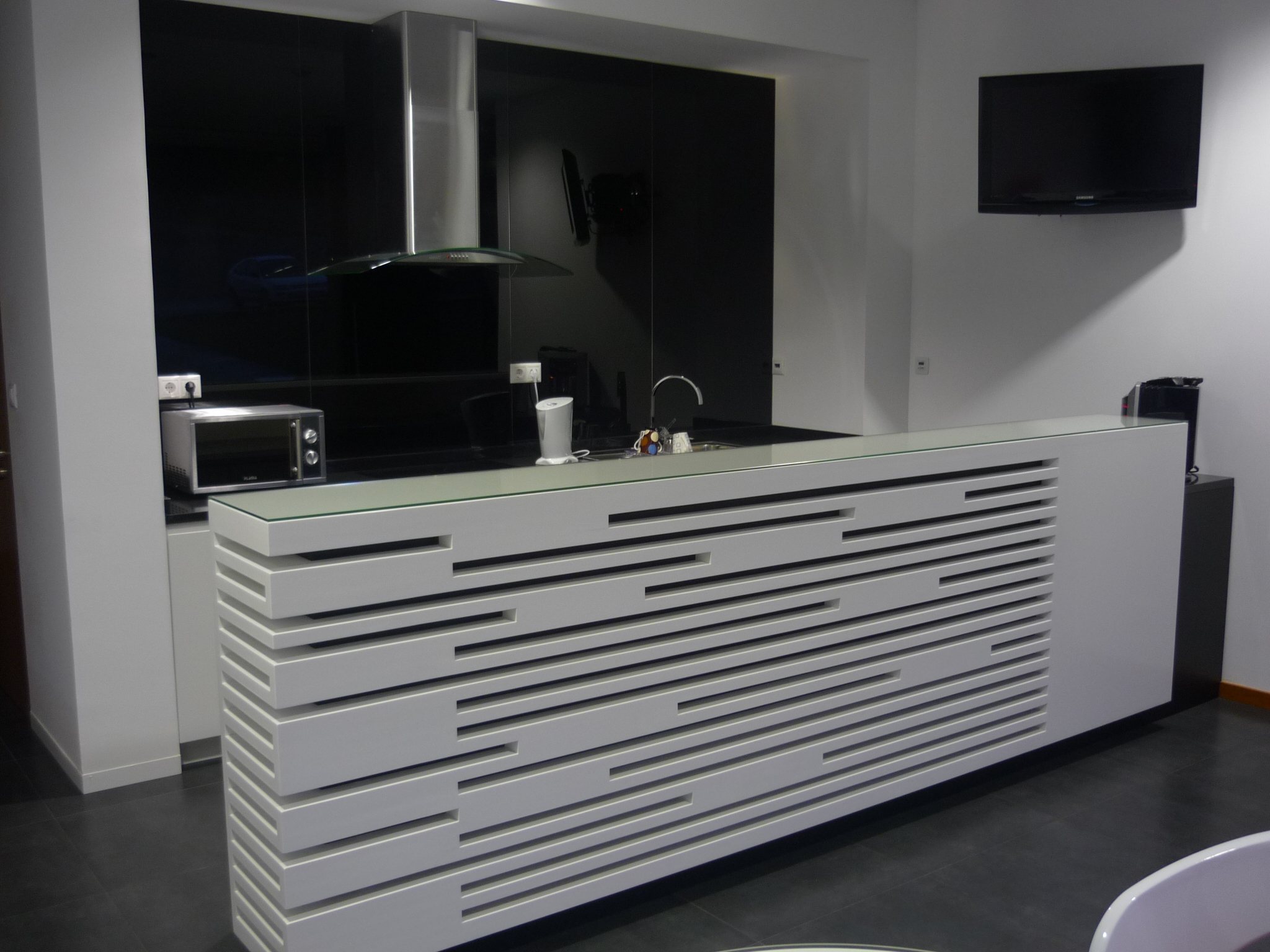 Balcao de recepcao com painel decorativo em ripas horizontais e tampo em vidro