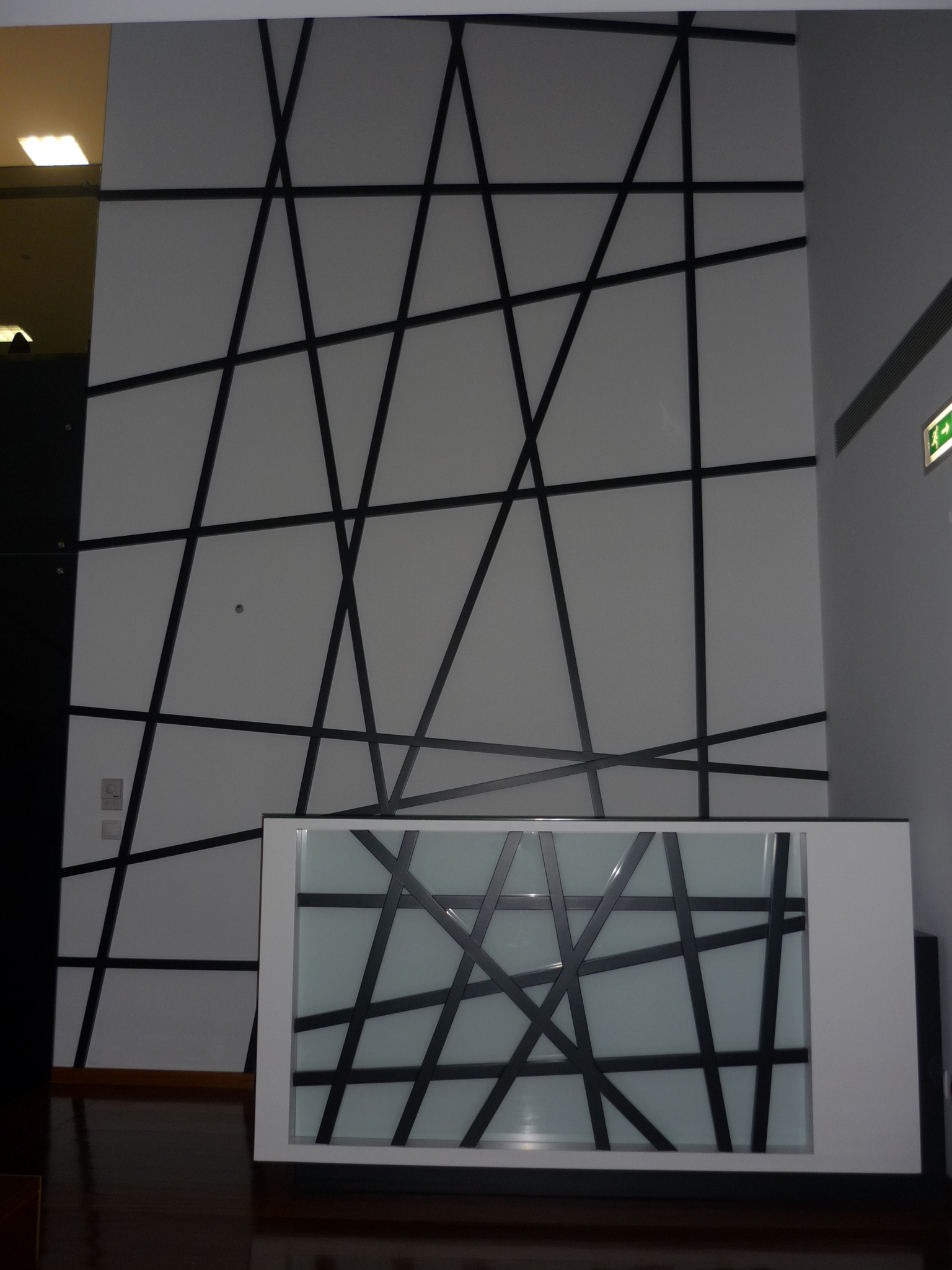 Balcao de recepcao com painel em linhas geometricas cruzadas e vidro retroiluminado