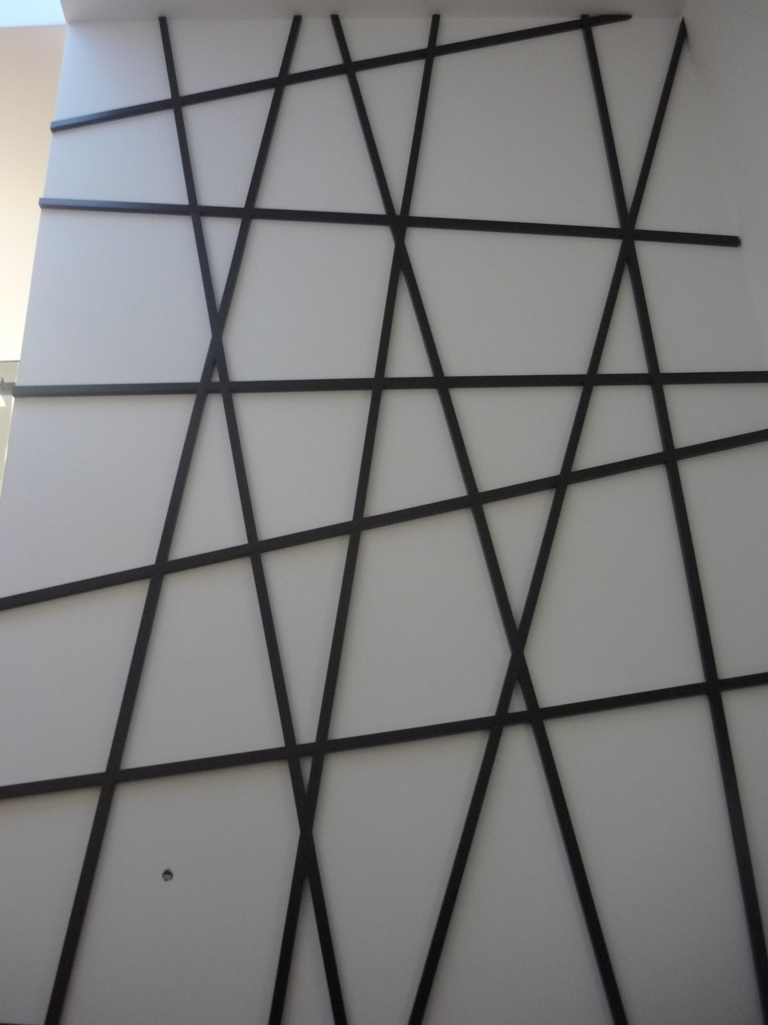 Detalhe frontal do balcao de recepcao com painel em vidro e linhas cruzadas