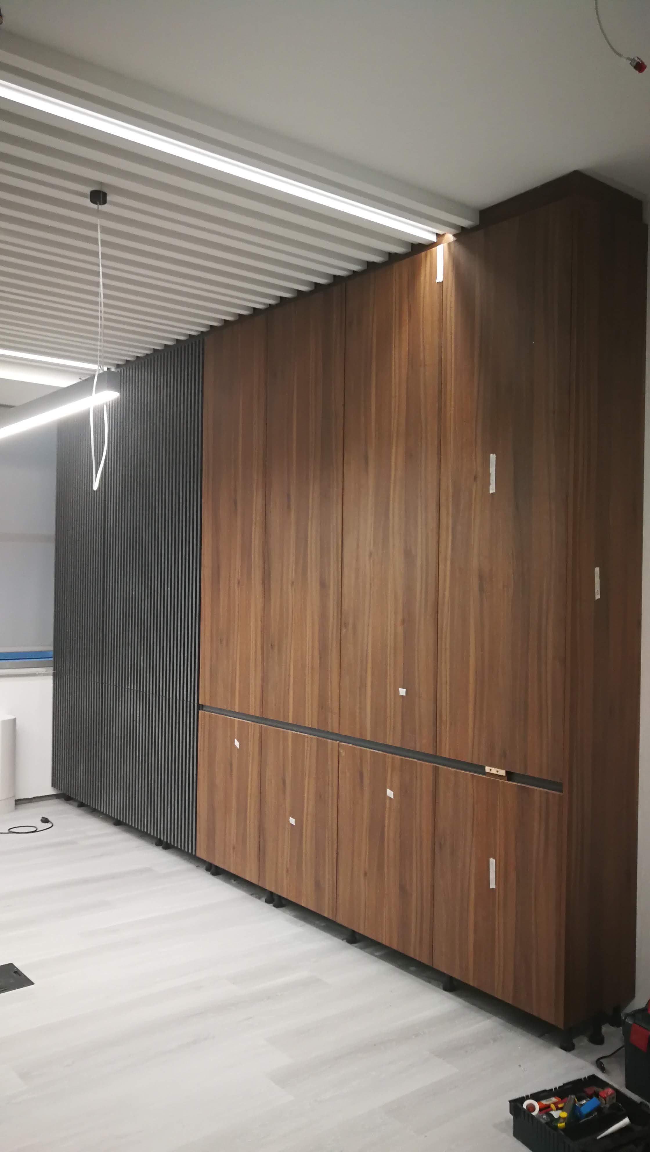 Armario de corpo inteiro em nogueira com paineis ripados escuros e iluminacao LED linear em fase de montagem