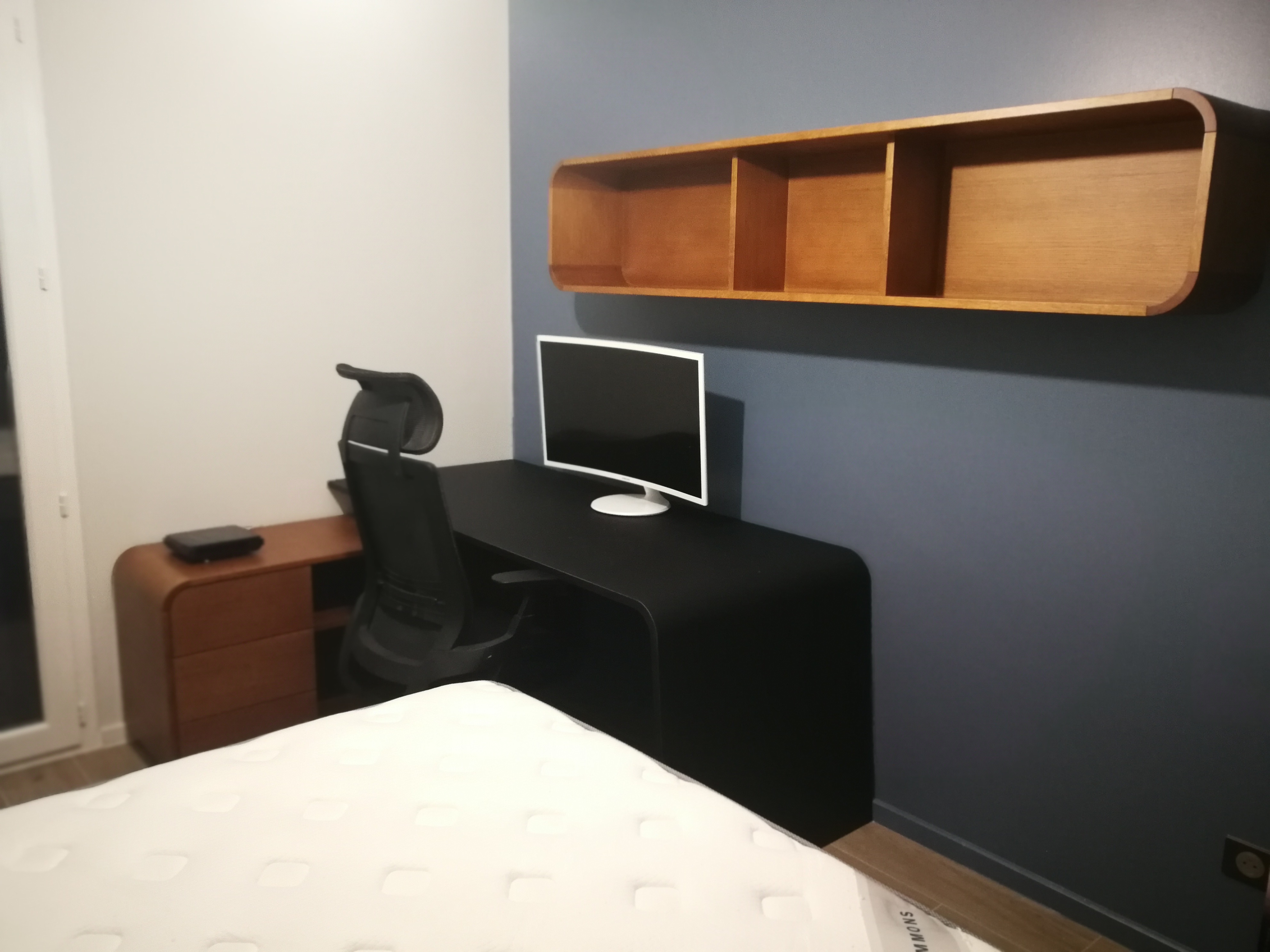 Quarto com secretaria preta suspensa, gaveteiro em carvalho e parede azul acinzentado