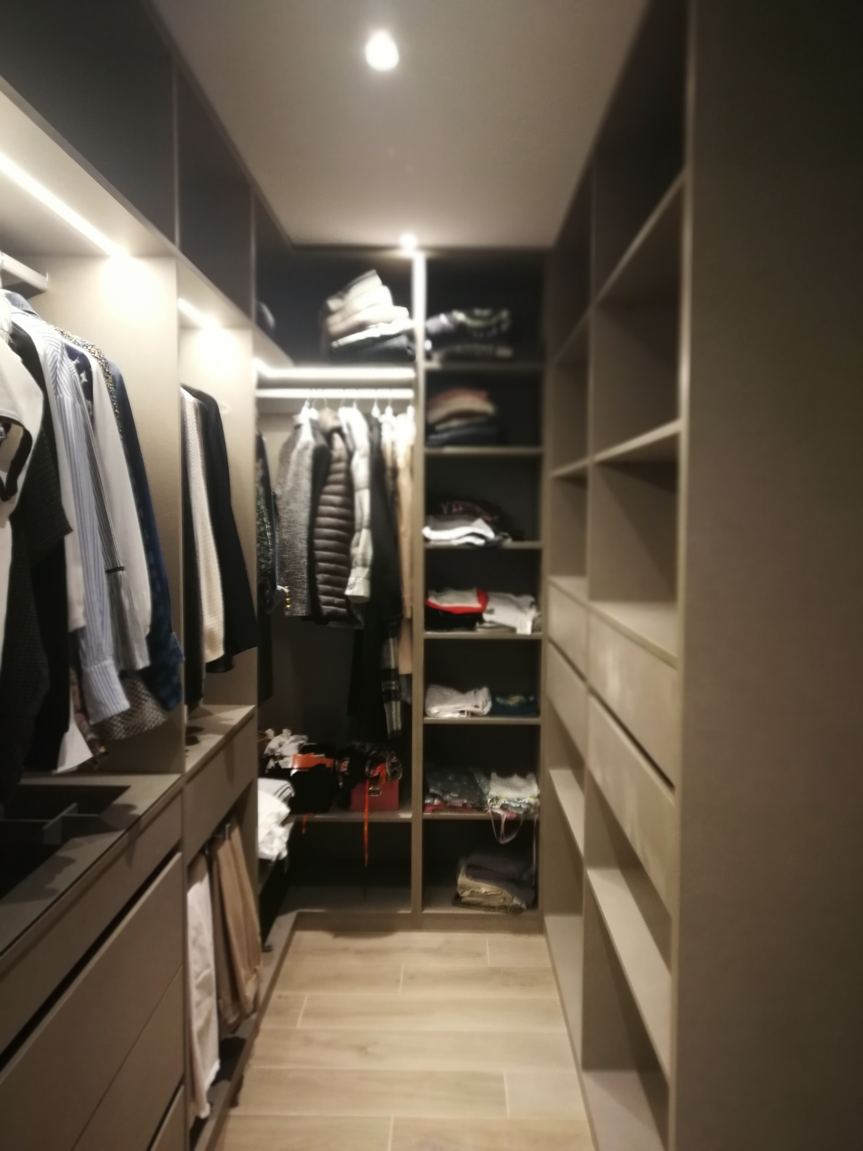 Closet walk-in com modulos cinza escuro, barras, prateleiras, gavetas e iluminacao LED