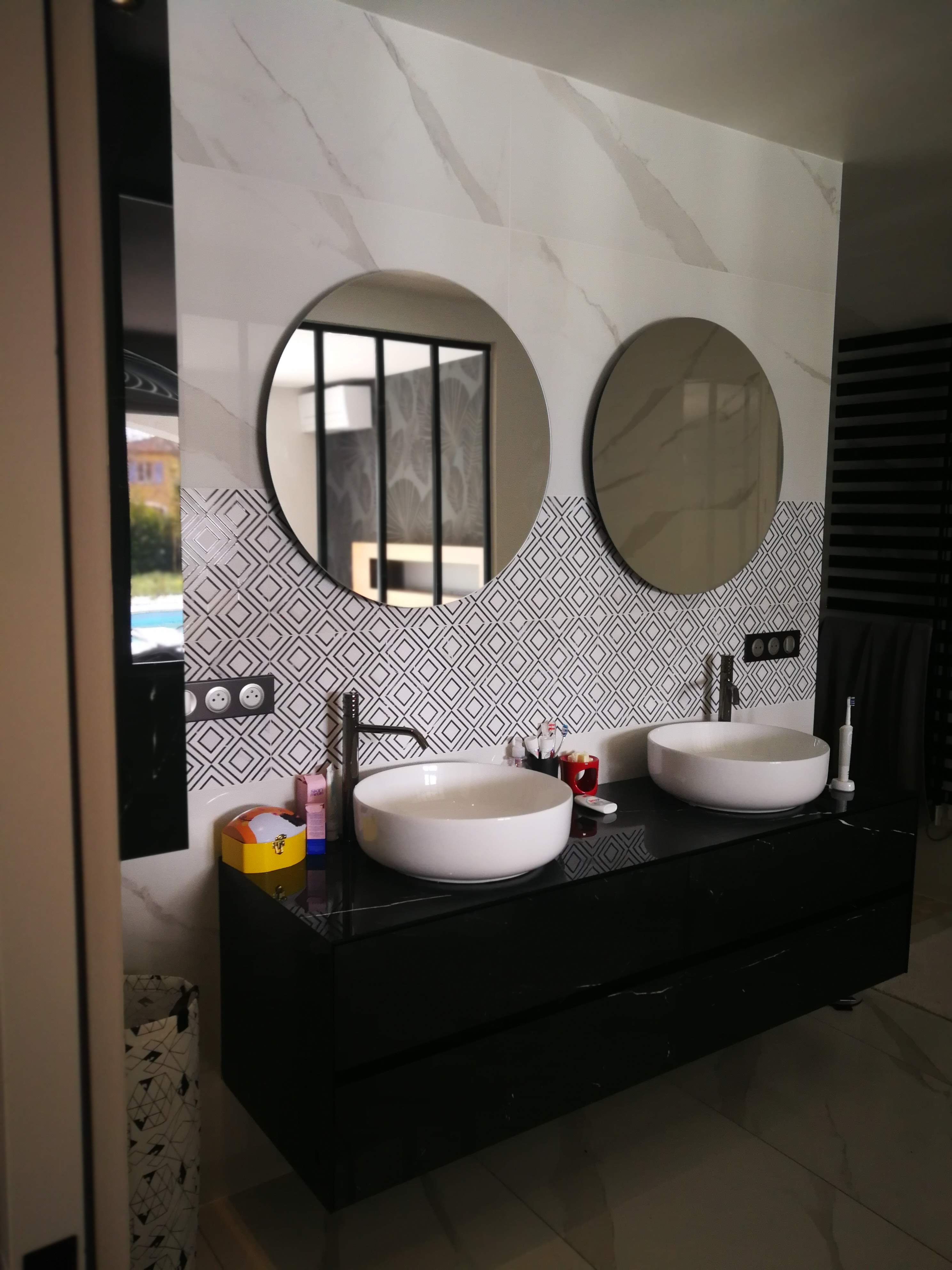 Casa de banho com duplo lavatorio redondo, espelhos redondos e azulejo geometrico preto e branco