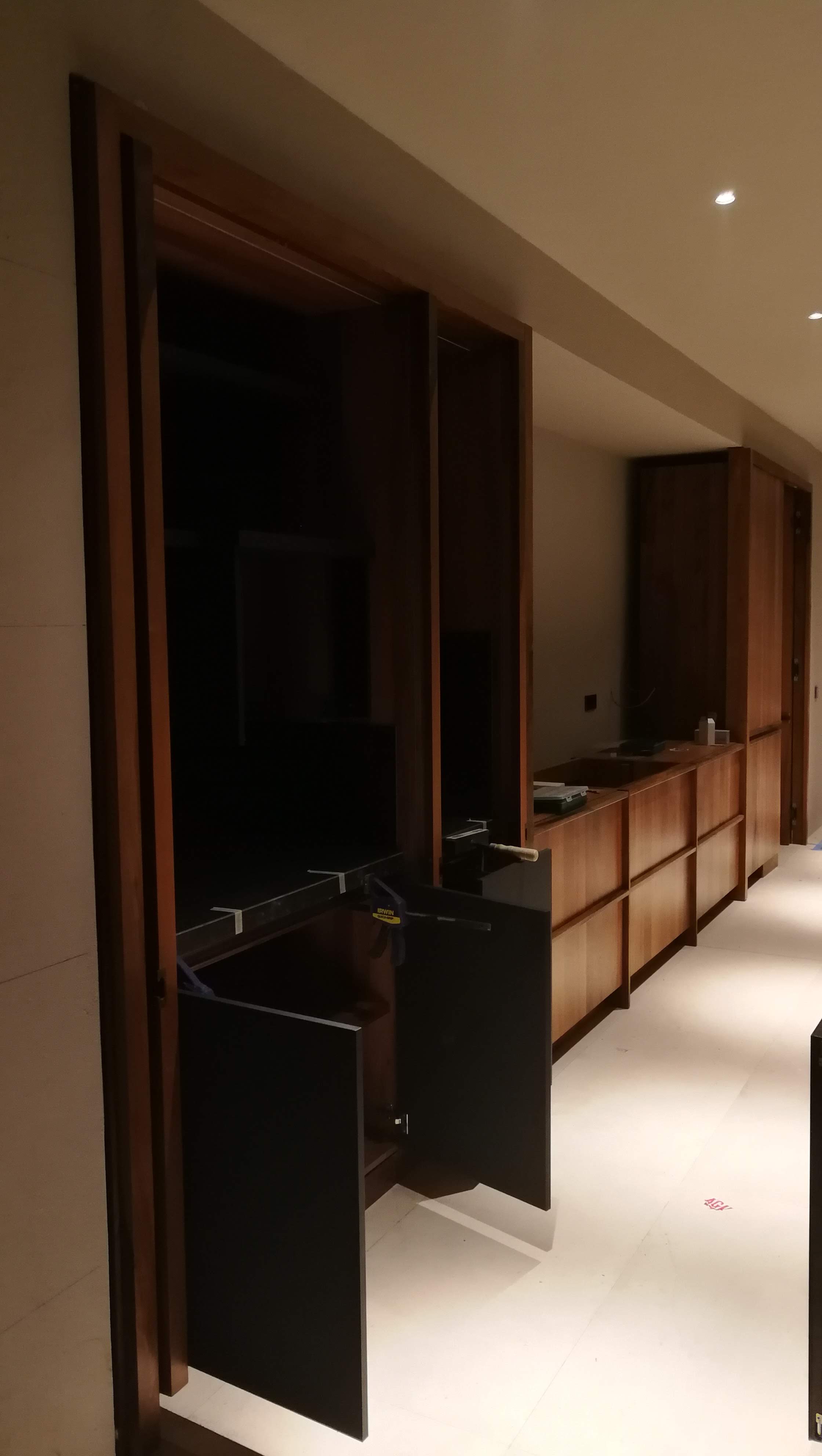 Corredor com movel baixo em madeira escura, envidracados em madeira e aparador com tampo preto