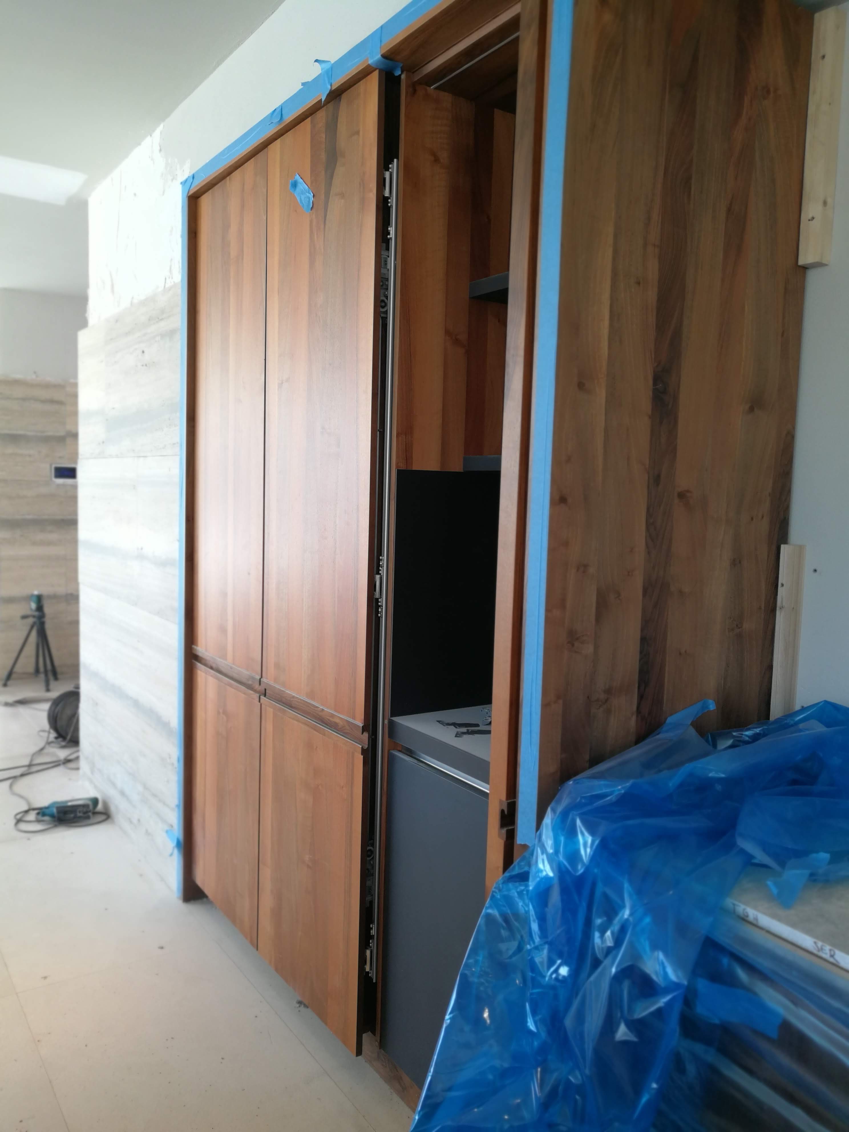 Armario alto em nogueira com frigorifico encastrado, em fase de instalacao com paredes em travertino