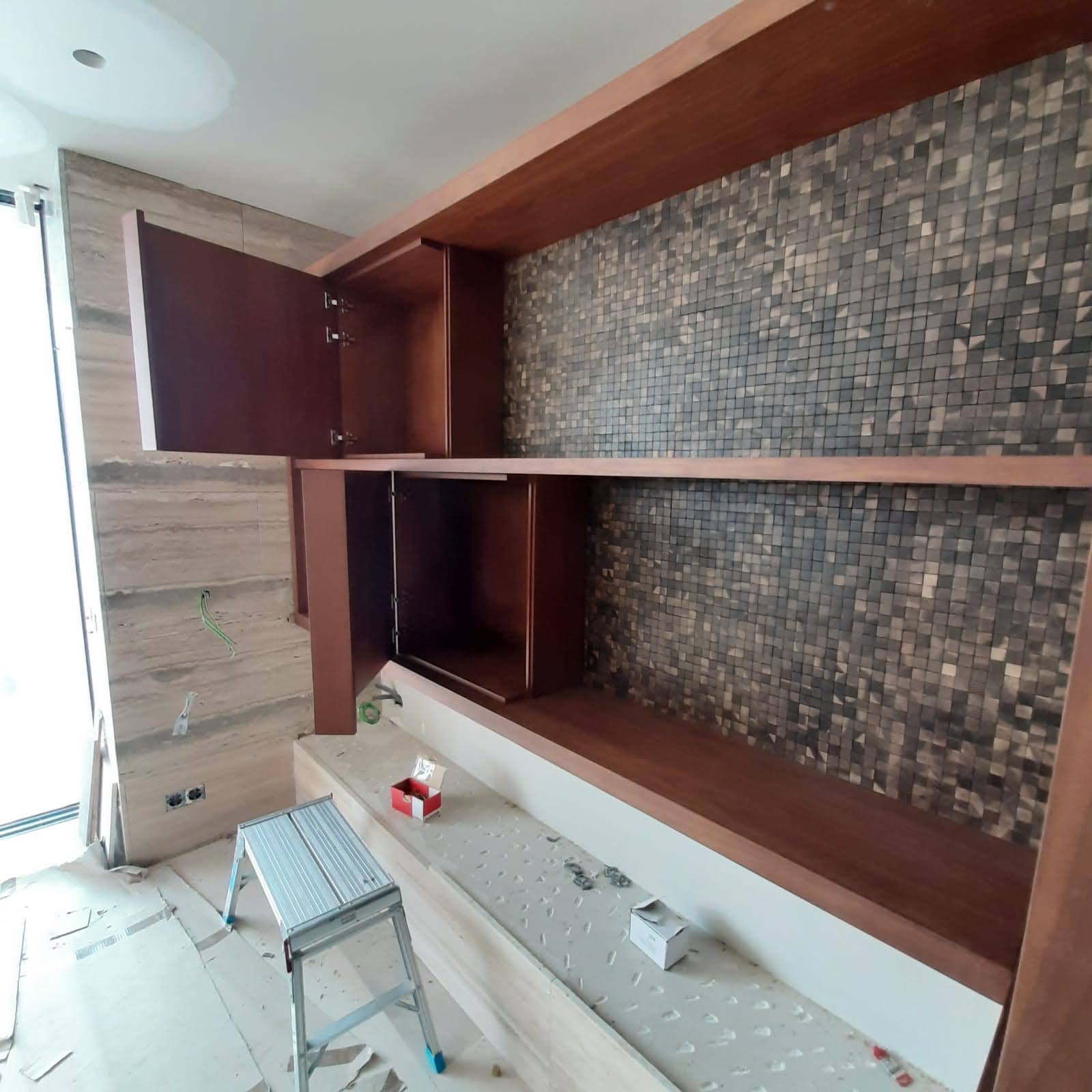 Movel de TV em nogueira com nichos, parede em mosaico cinza e dourado e bancada em travertino