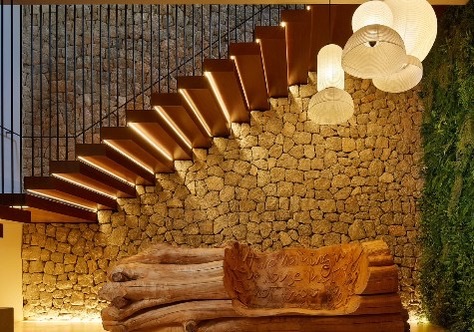 Escadaria com degraus flutuantes em madeira e aco corten, parede de pedra e candeeiros esfericos