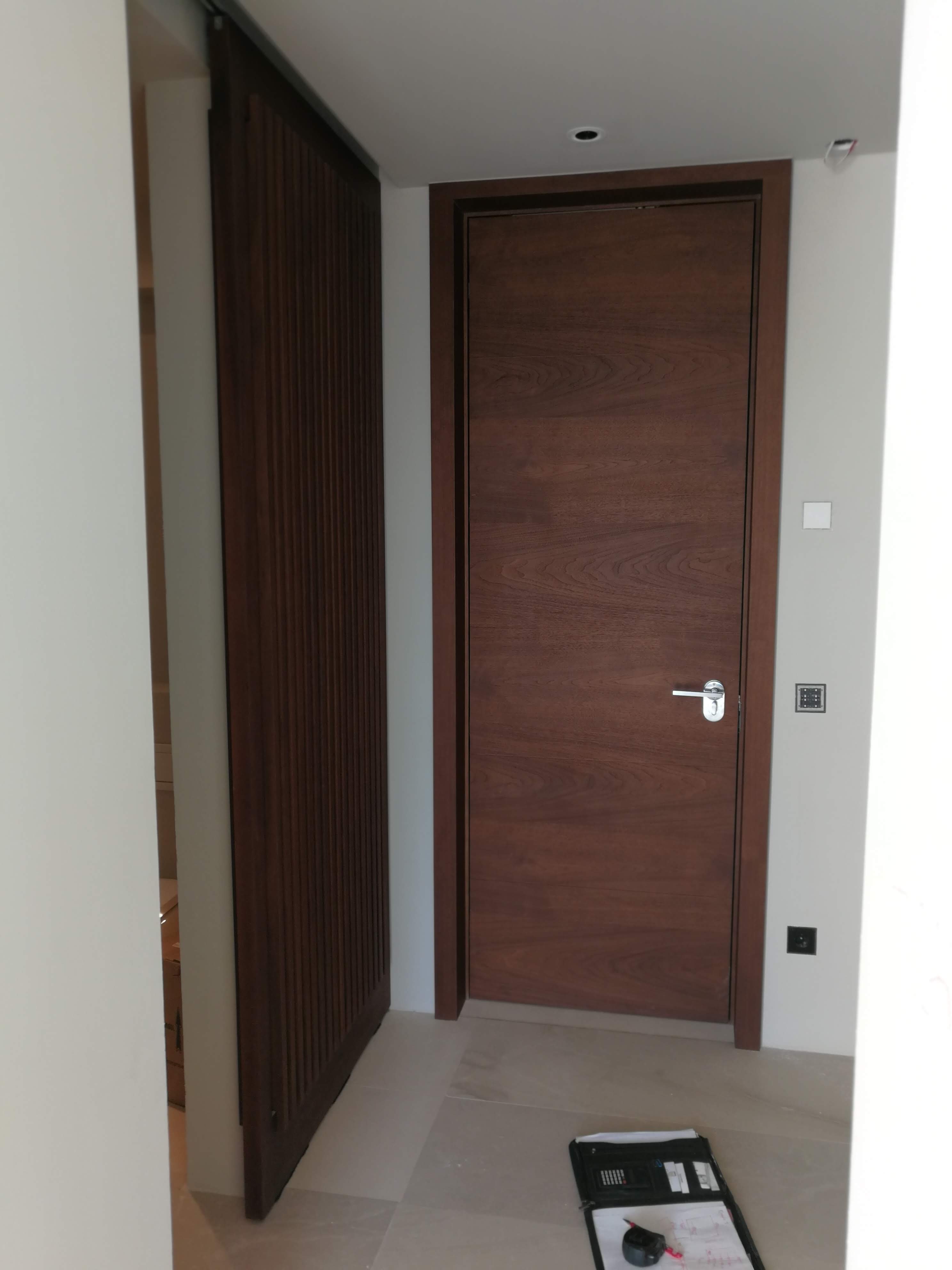 Corredor com porta em nogueira, divisoria em ripas de madeira e paredes brancas