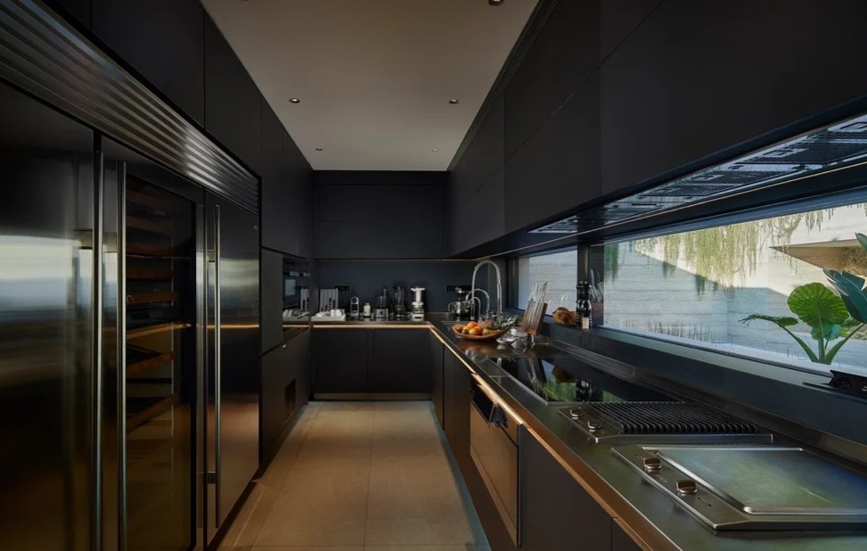 Cozinha profissional em preto e aco inoxidavel com bancadas escuras e frigorifico encastrado