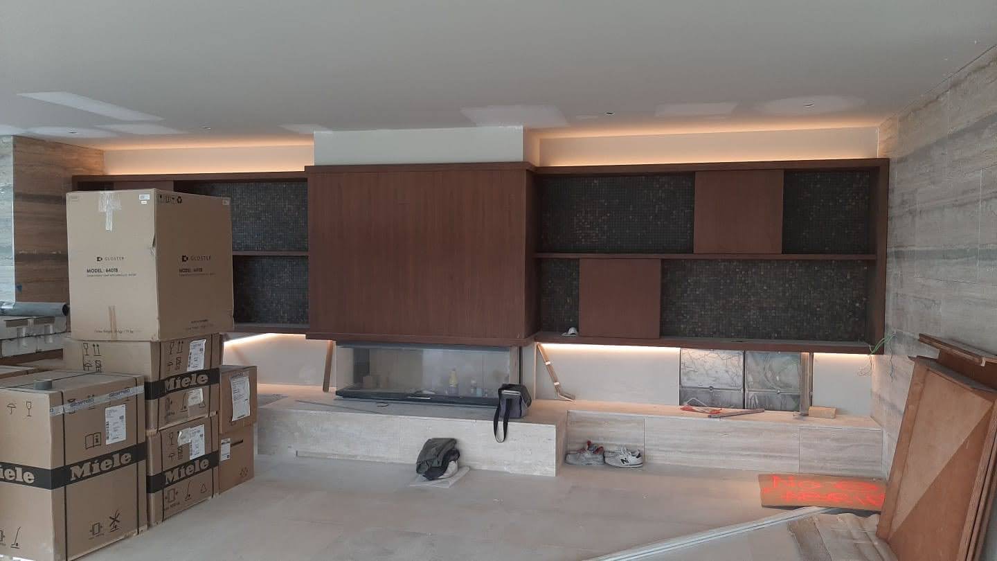 Sala com movel de parede em madeira e mosaico decorativo escuro, lareira linear com LED