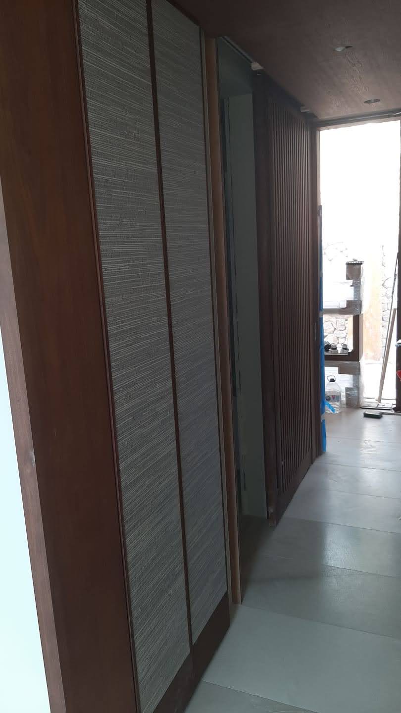 Corredor com armarios de portas de correr em tecido cinza com molduras em madeira e painel ripado