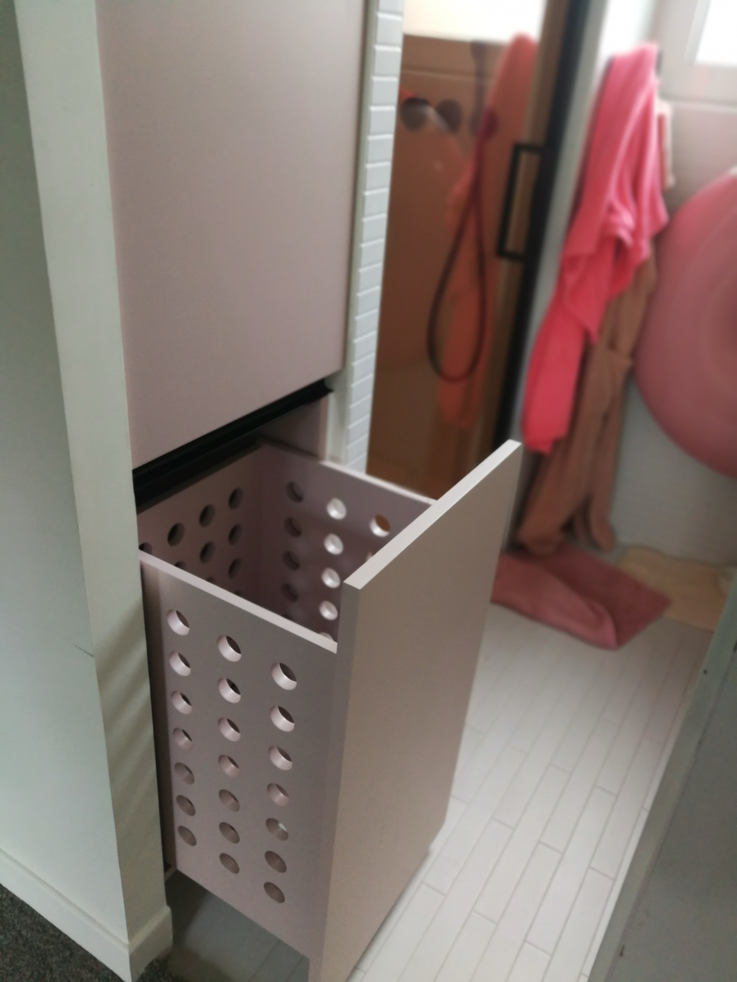 Casa de banho com cesto de roupa integrado em movel branco e base de duche em azulejo branco