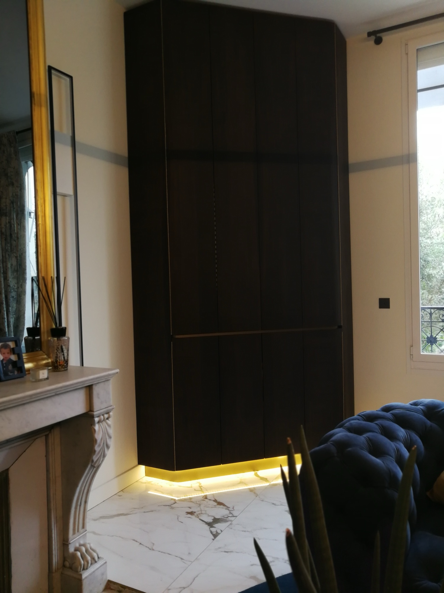 Armario de canto em madeira escura com LED junto a lareira em marmore e sofa Chesterfield