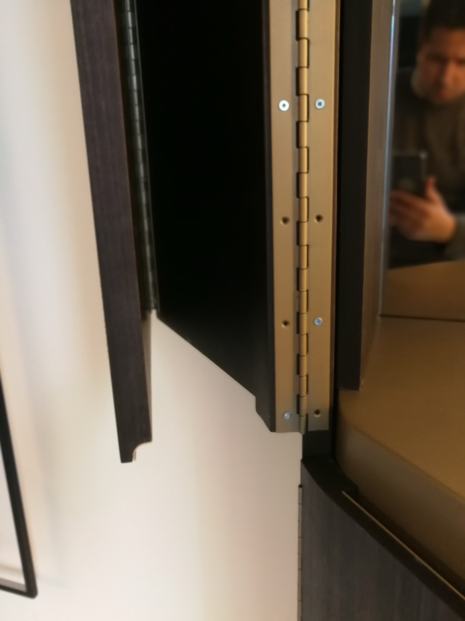 Detalhe de dobradica em latao do movel de sala em madeira escura