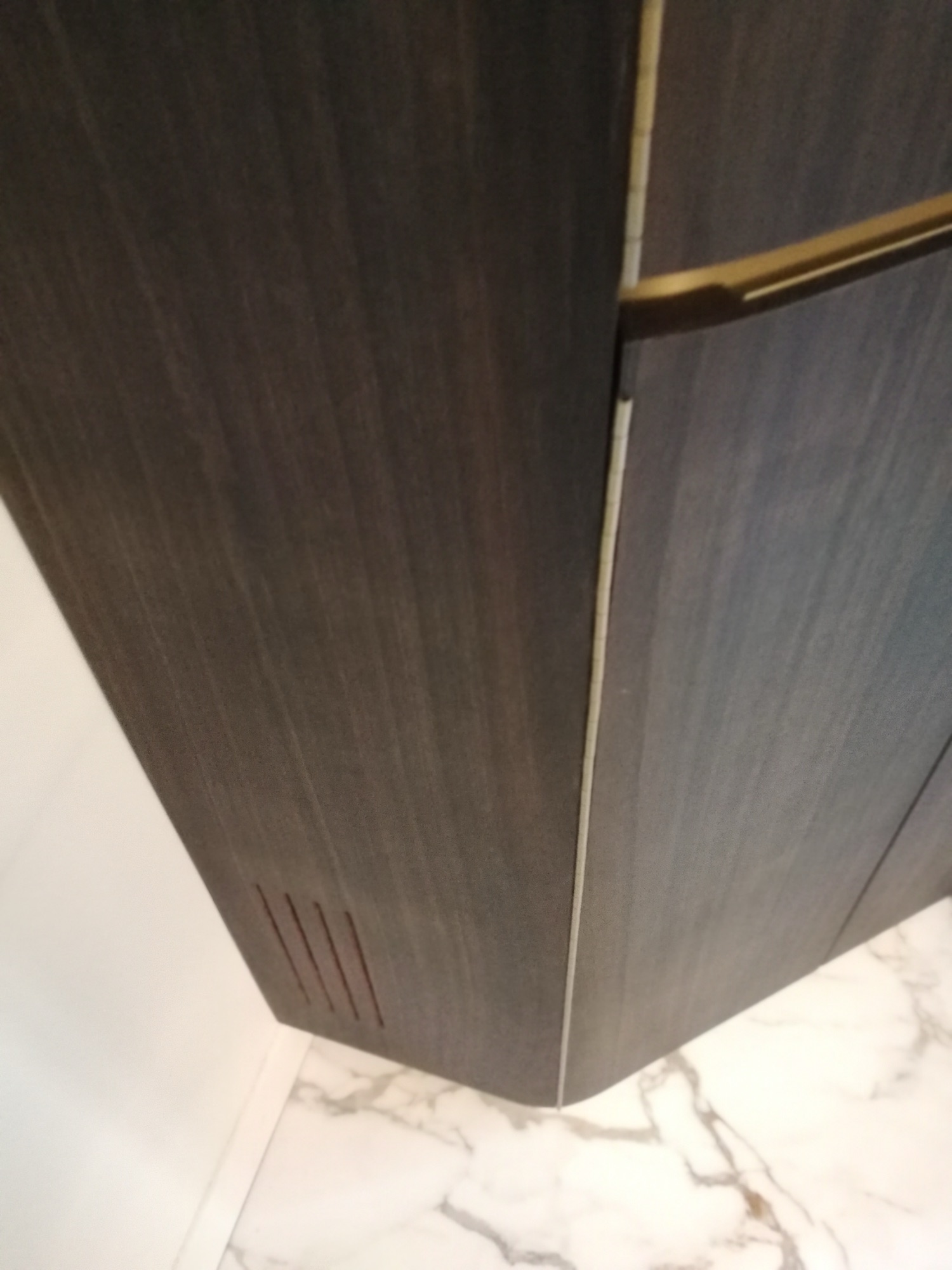 Detalhe da base do armario em wenge com acabamento e grelha de ventilacao sobre porcelanato marmore