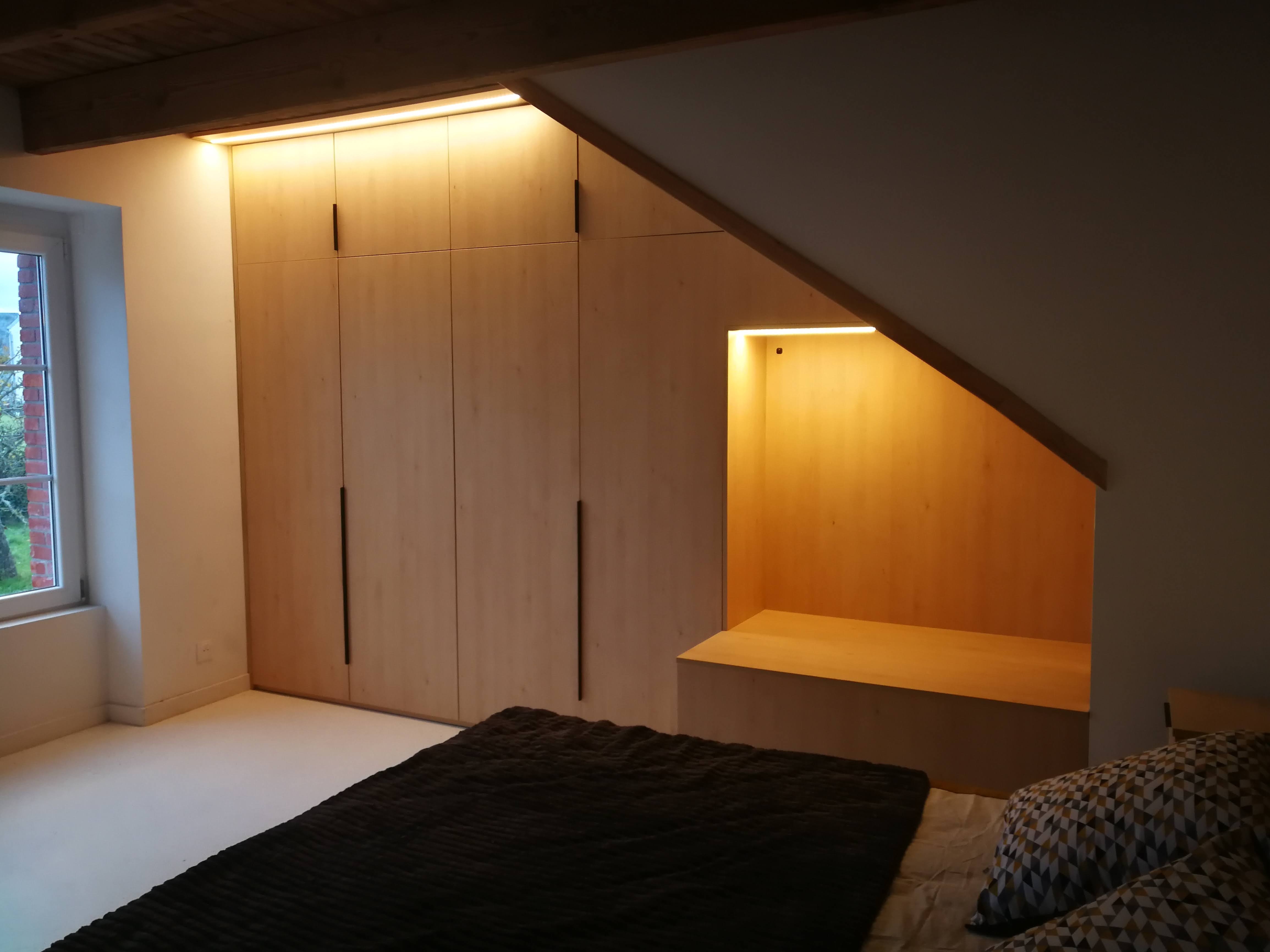 Quarto em sotao com armario embutido em madeira clara adaptado ao teto inclinado com vigas, nicho iluminado