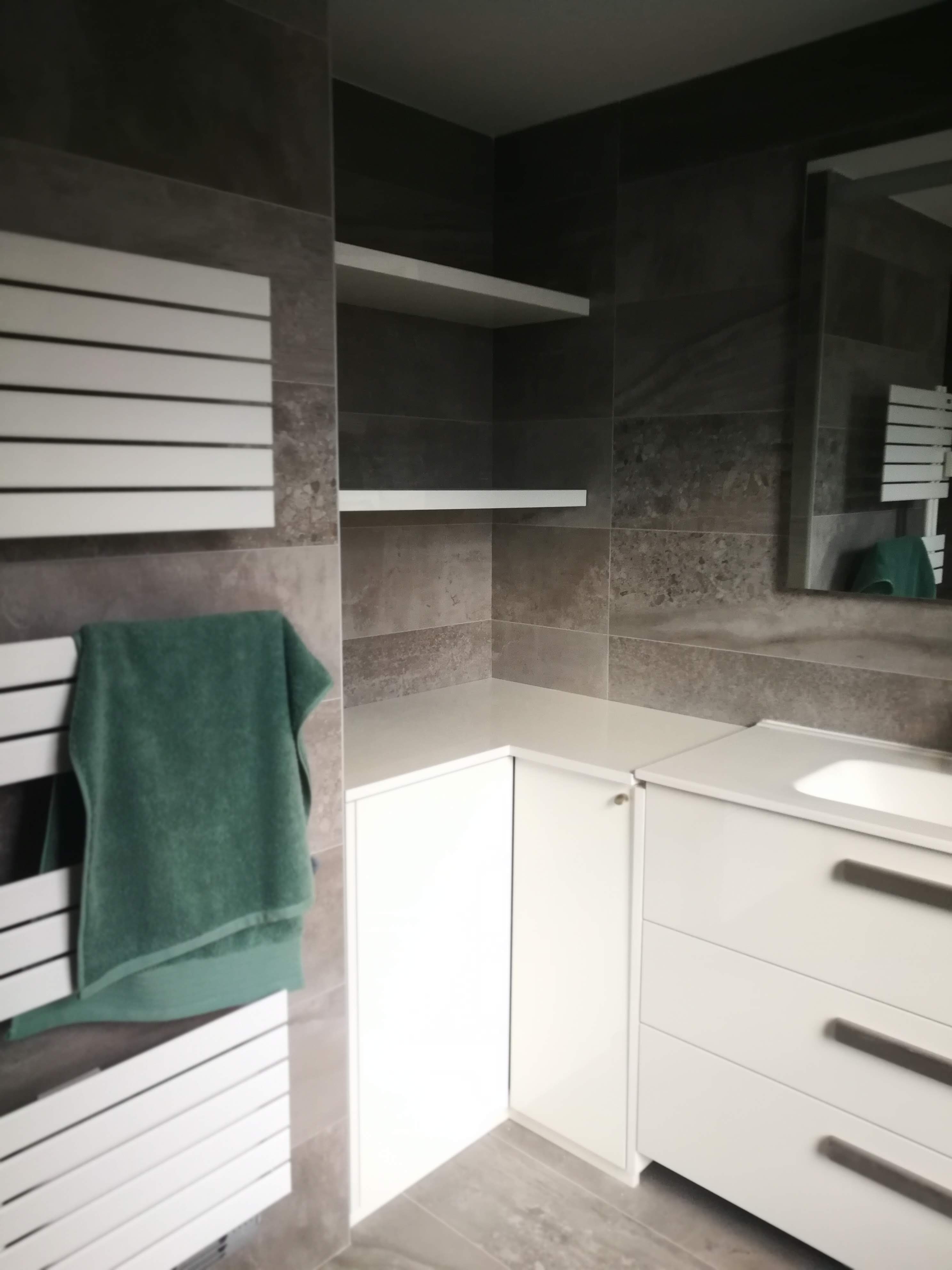 Casa de banho com azulejo cinza-escuro, toalheiro radiante branco e movel de lavatorio branco